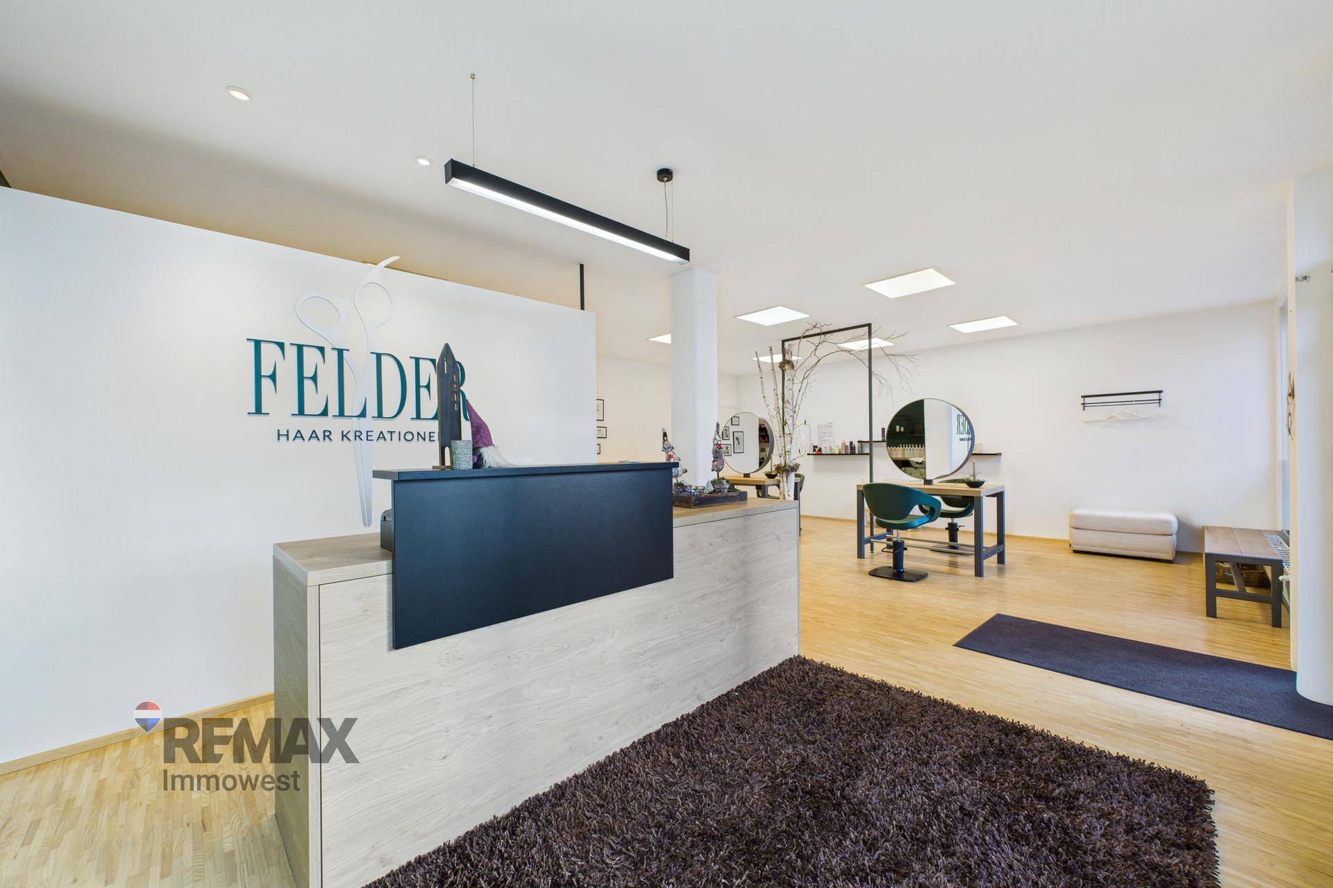Geräumiger Empfangs- und Arbeitsbereich eines Friseursalons mit hellem Ambiente und modernen Möbeln.