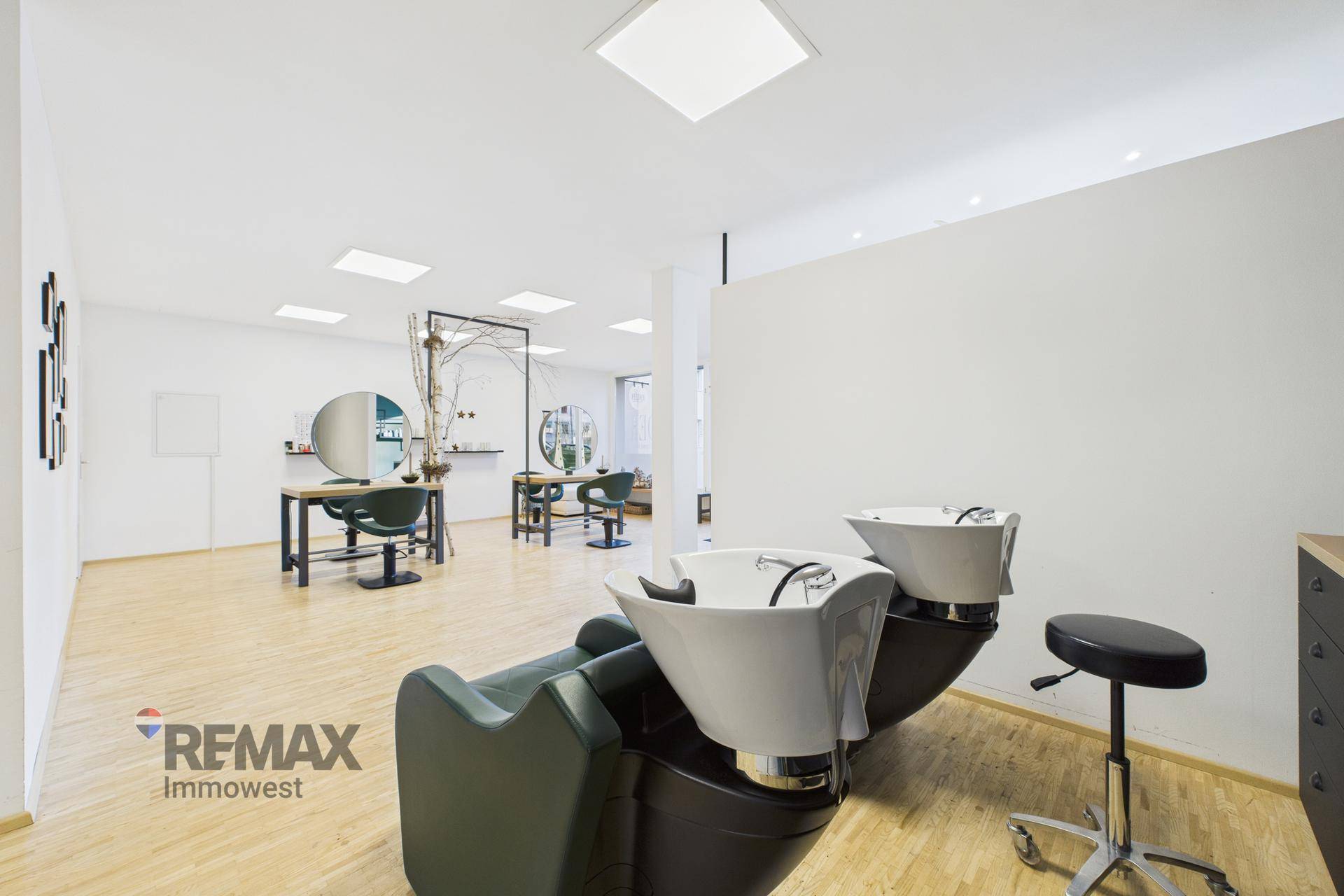 Blick vom Haarwaschbereich in den Hauptsalon mit mehreren Frisierplätzen und hellem Ambiente.