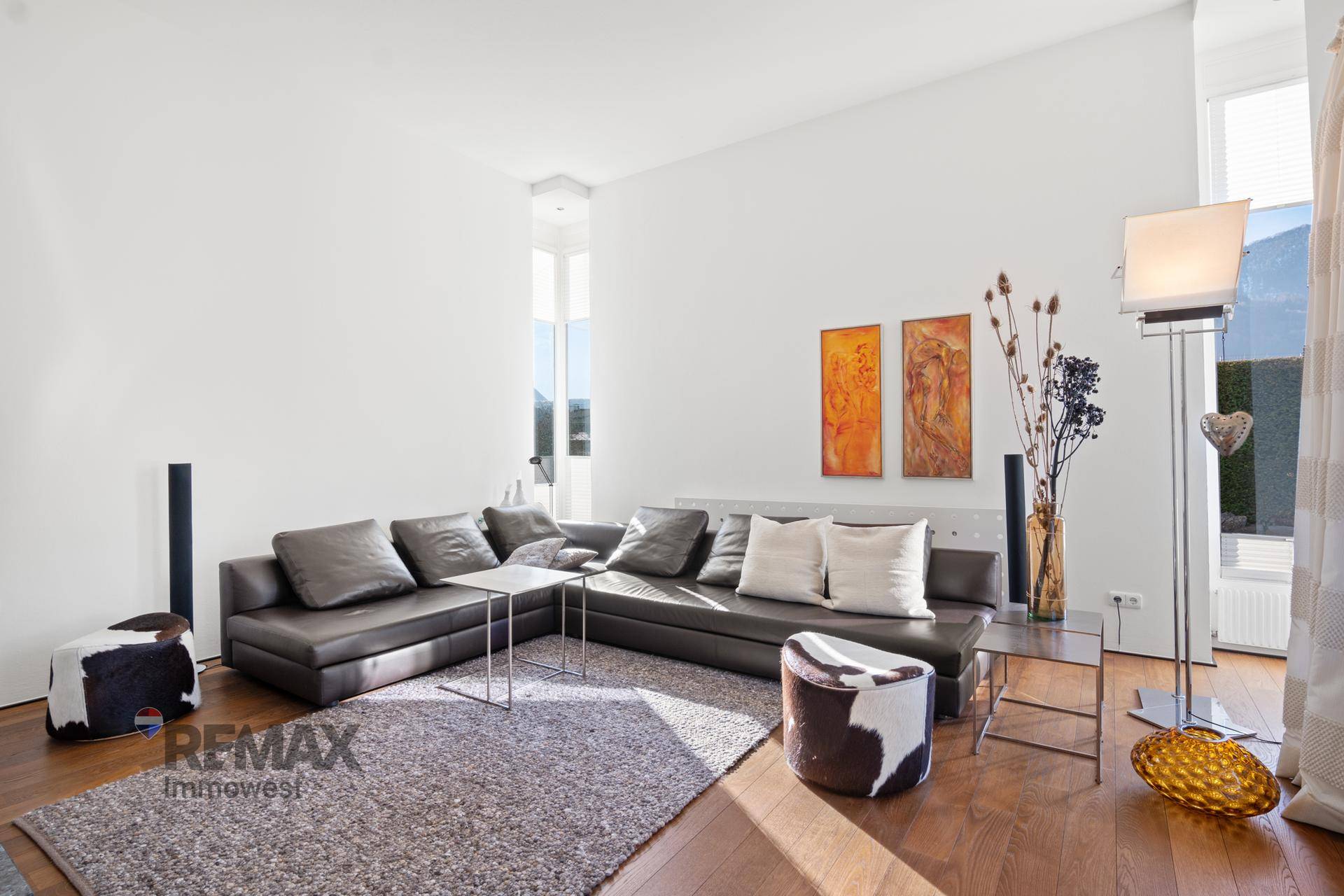 Gemütliches Wohnzimmer mit großem Ecksofa, Holzboden und viel natürlichem Licht.