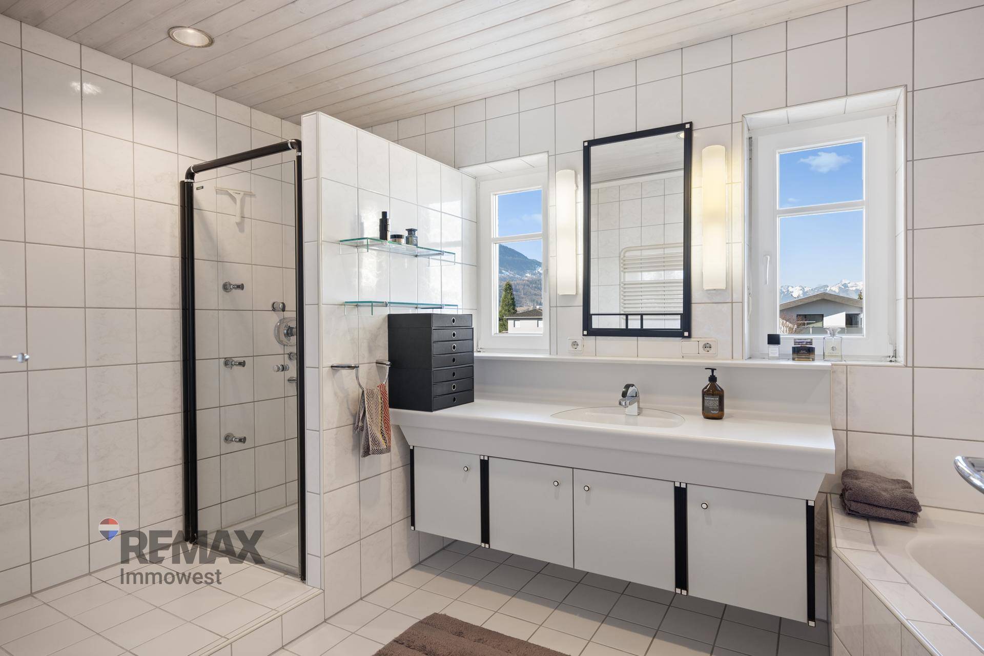 Geräumiges Badezimmer mit Dusche, Badewanne, Doppelwaschbecken und Fenster.