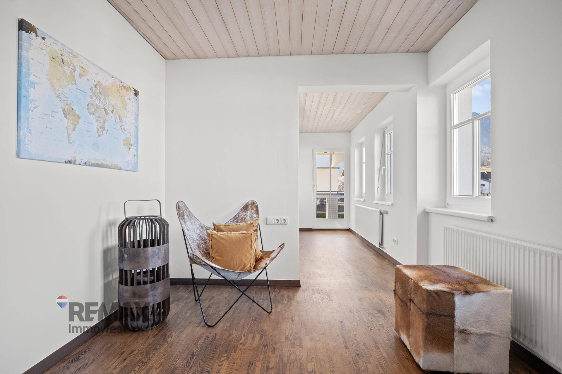 Vielseitiger Raum mit Holzboden, Weltkarte an der Wand und Zugang zu weiteren Bereichen.