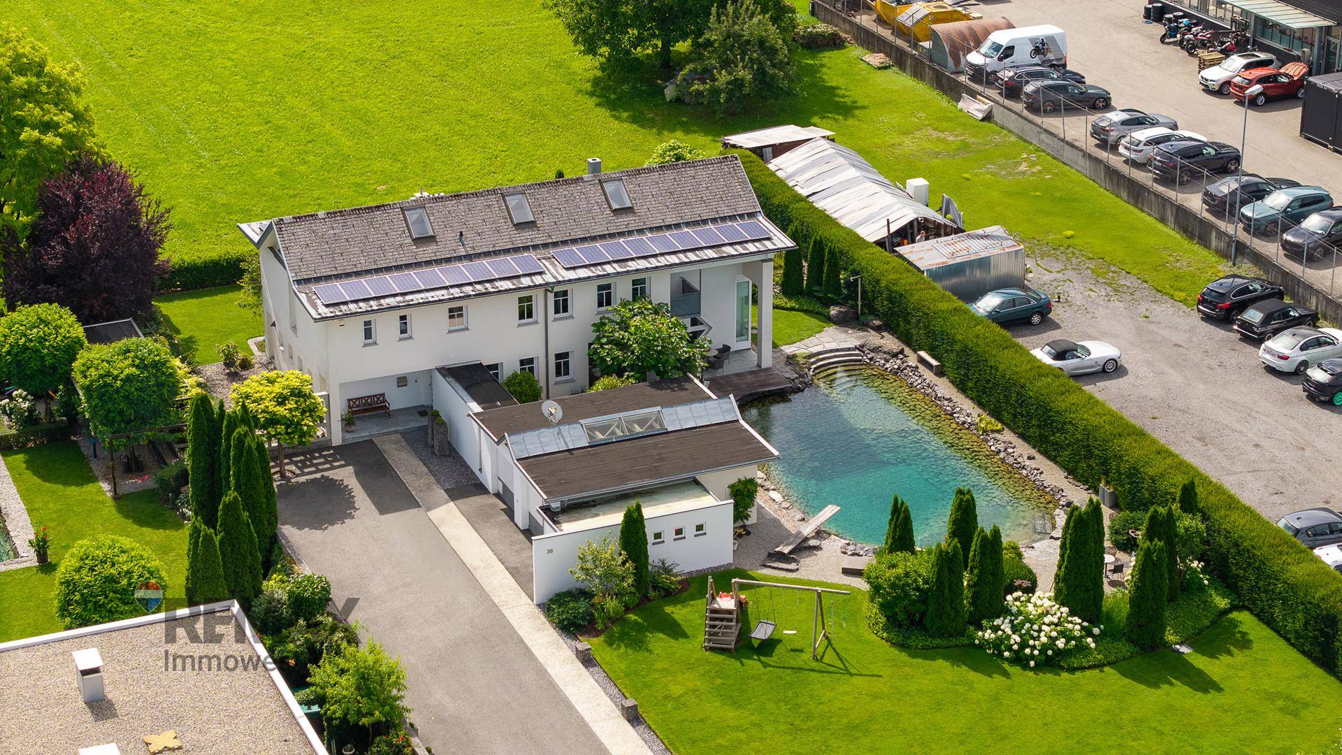 Luftaufnahme des Anwesens mit großem Garten, Schwimmteich und Photovoltaikanlage auf dem Dach.