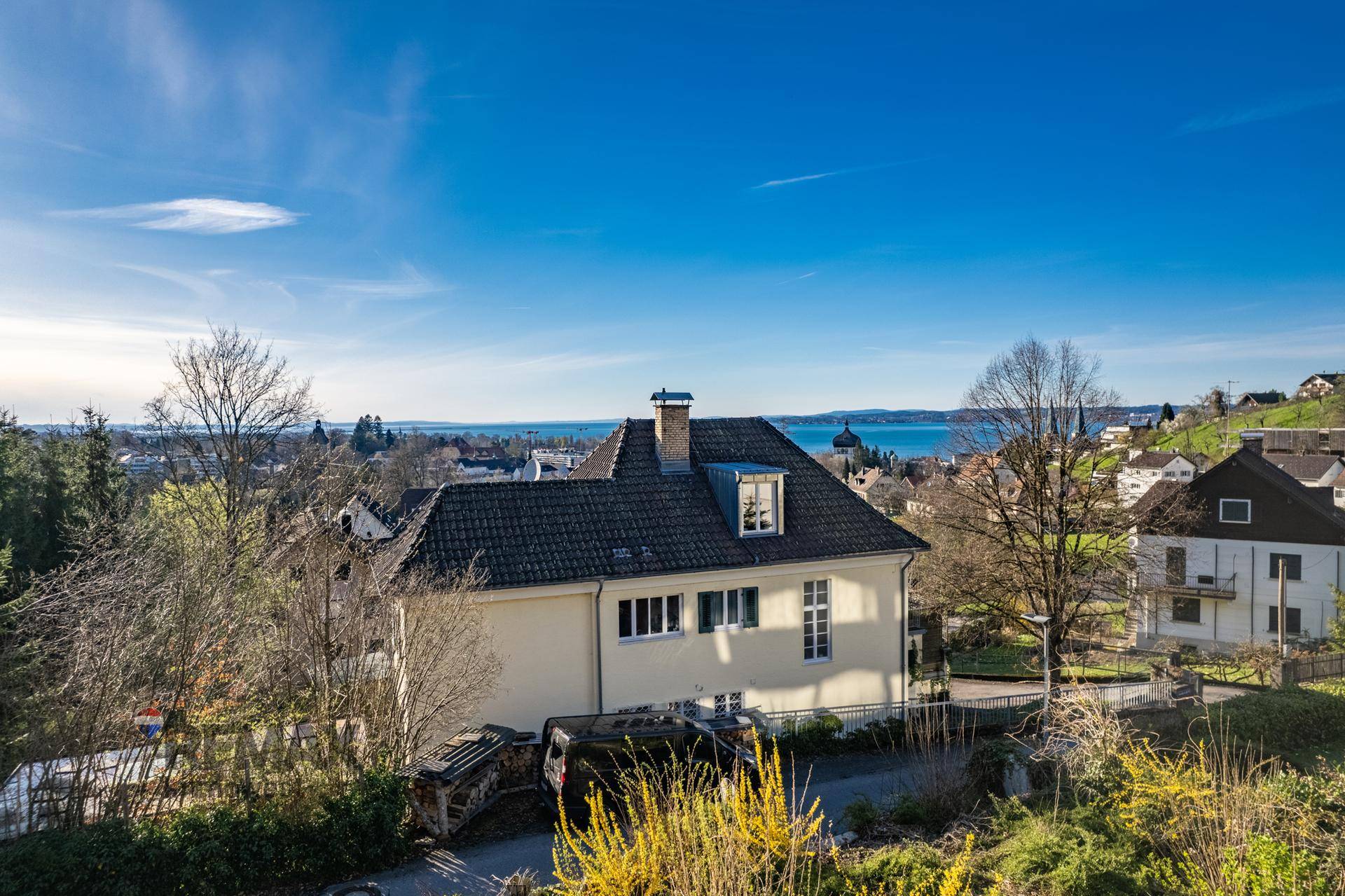 Hausfassade mit traditionellem Dach und weitem Blick auf den See und die Umgebung.