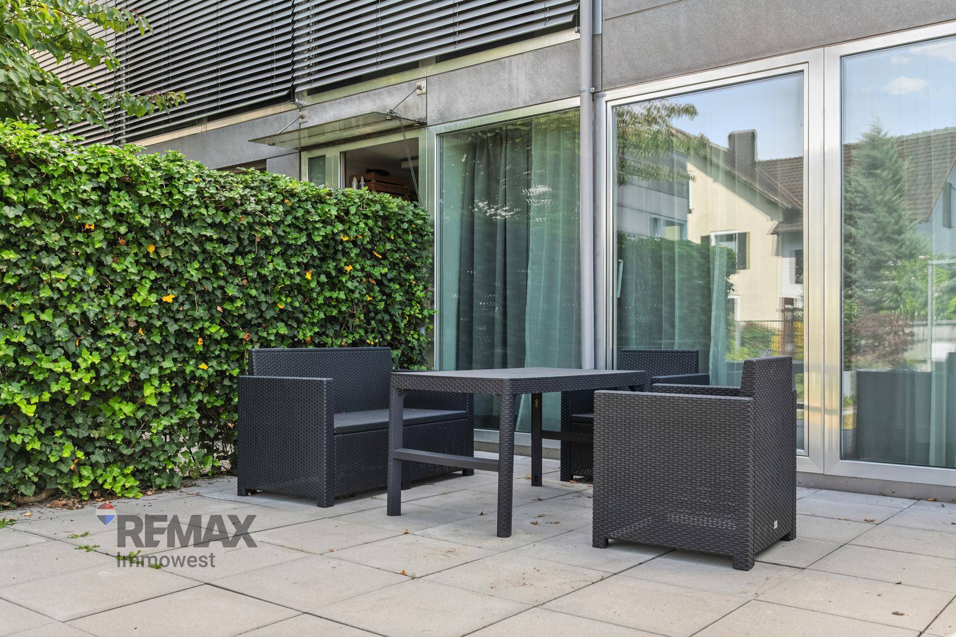 Gemütliche Terrasse mit modernen Outdoor-Möbeln und grüner Hecke für Privatsphäre.