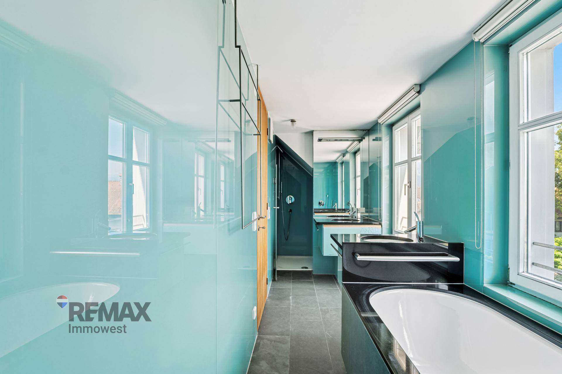 Großes modernes Badezimmer mit Badewanne, Dusche, Doppelwaschbecken und türkisfarbenen Wänden.