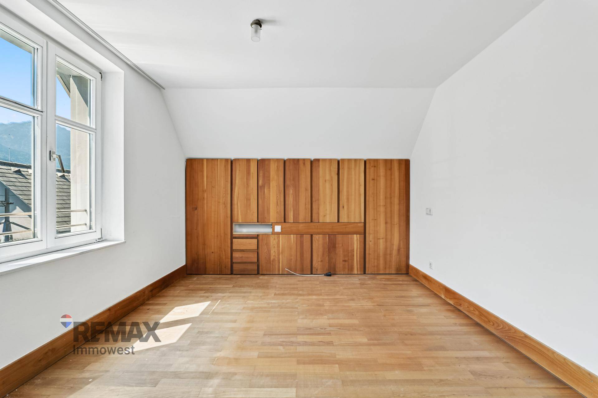 Geräumiges Schlafzimmer mit Holzboden, Einbauschränken und viel natürlichem Licht.