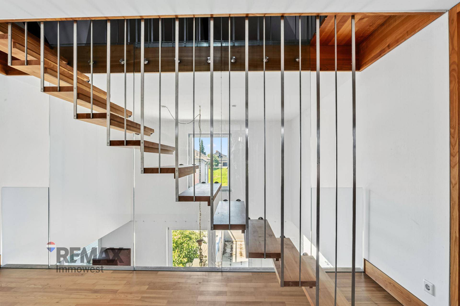 Elegante schwebende Holztreppe mit filigranem Metallgeländer und viel Tageslicht.