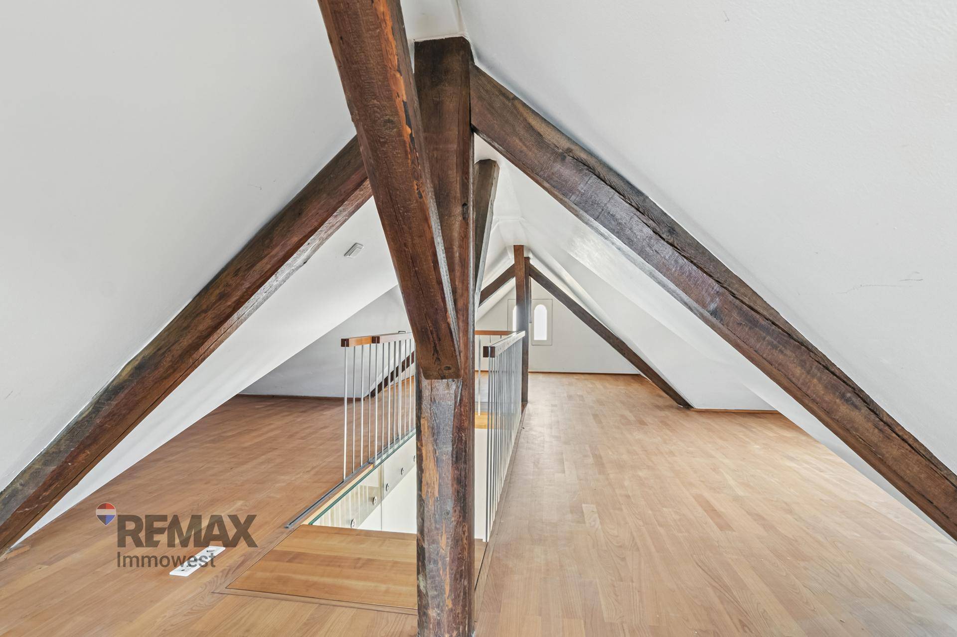 Ausgebauter Dachboden mit sichtbaren Holzbalken, Holzboden und offener Galerie.