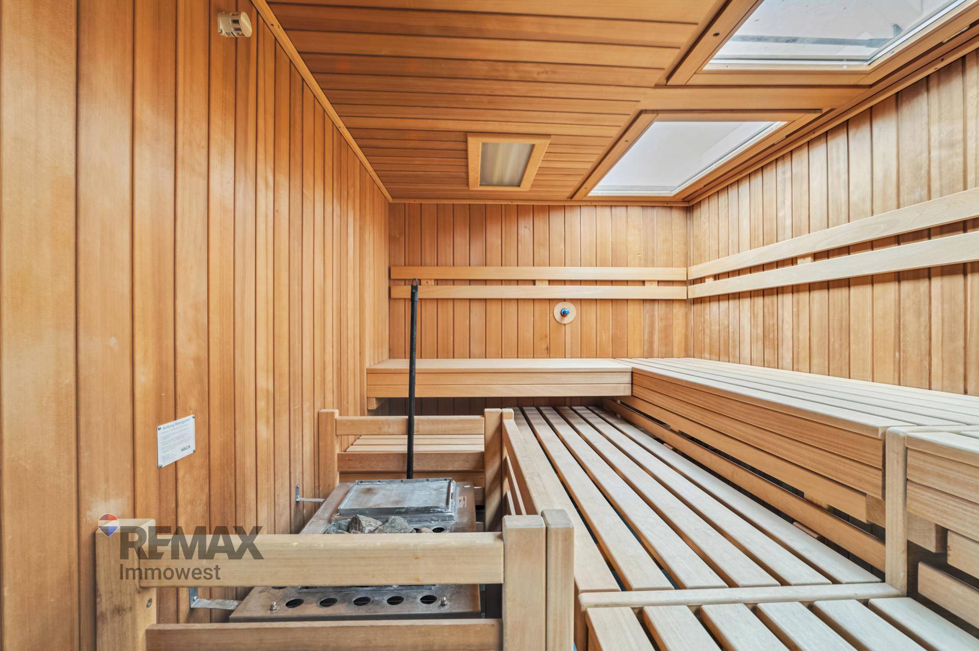 Geräumige Holzsauna mit mehreren Bänken und integriertem Ofen für Entspannung.