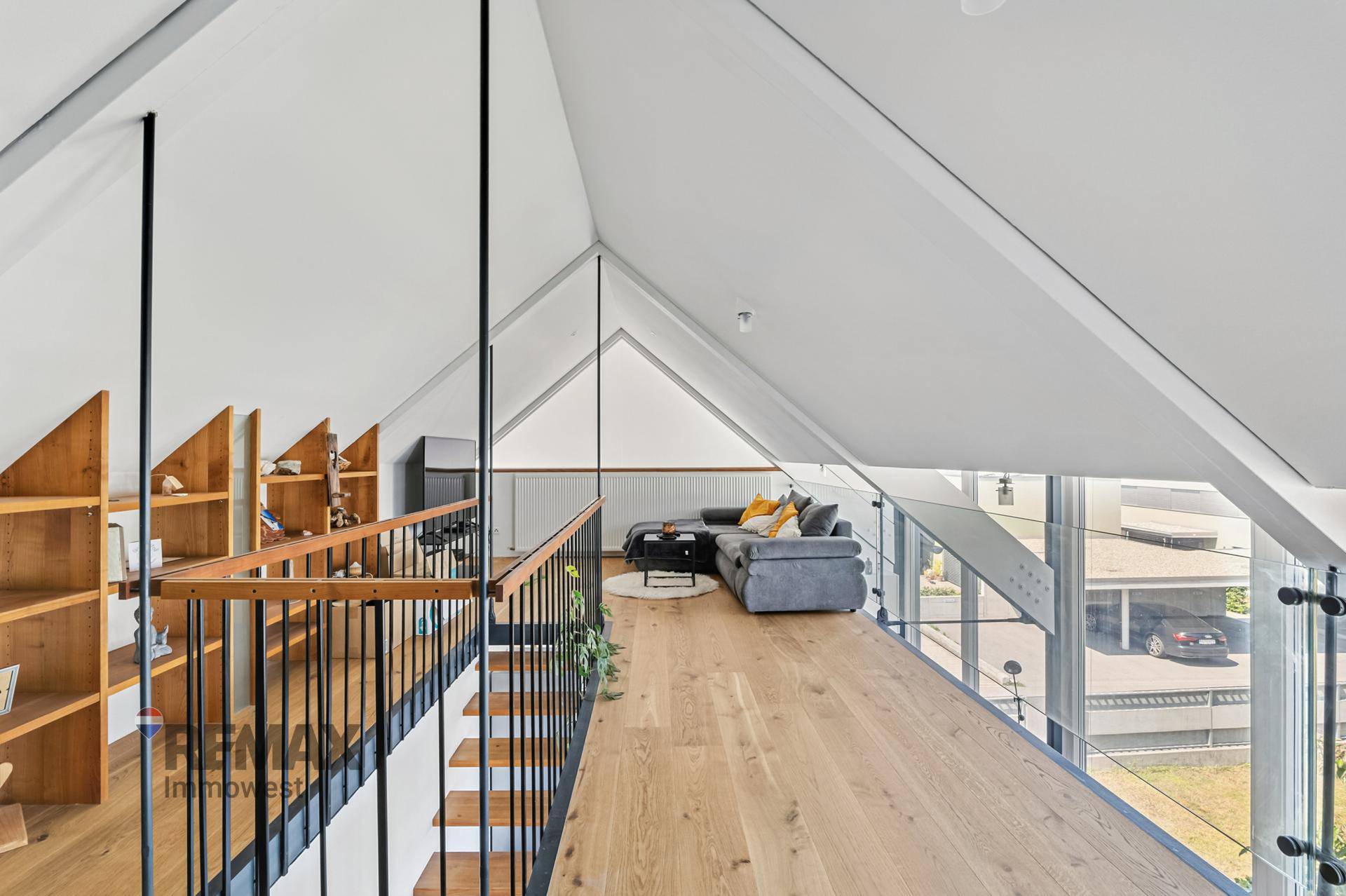 Gemütlicher Wohnbereich im Dachgeschoss mit Holzboden, Sofa und Blick auf die Umgebung.