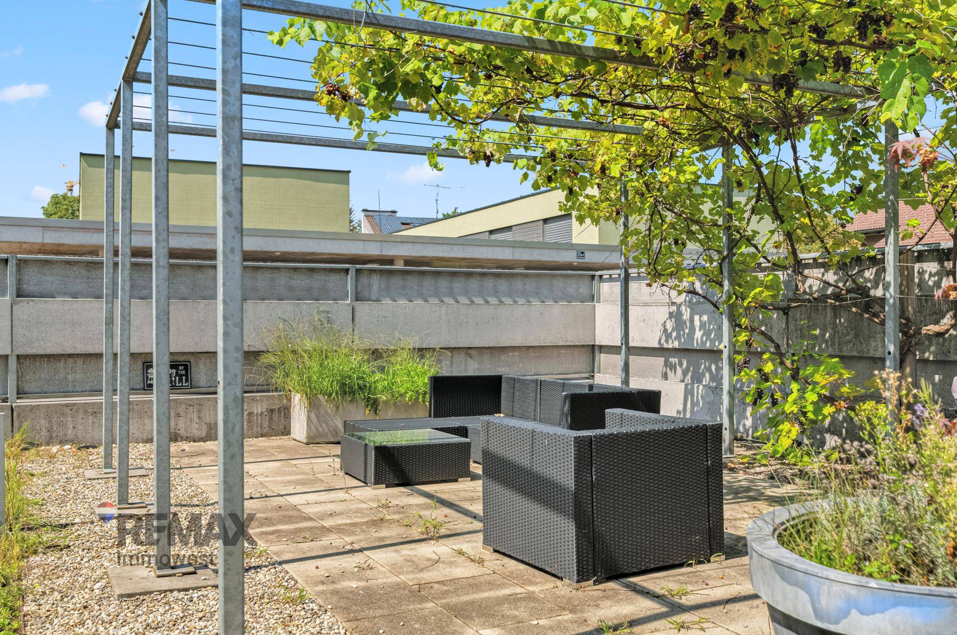 Gemütliche Terrasse mit Pergola und Sitzgelegenheiten, umgeben von Pflanzen und mit Blick auf die Umgebung.