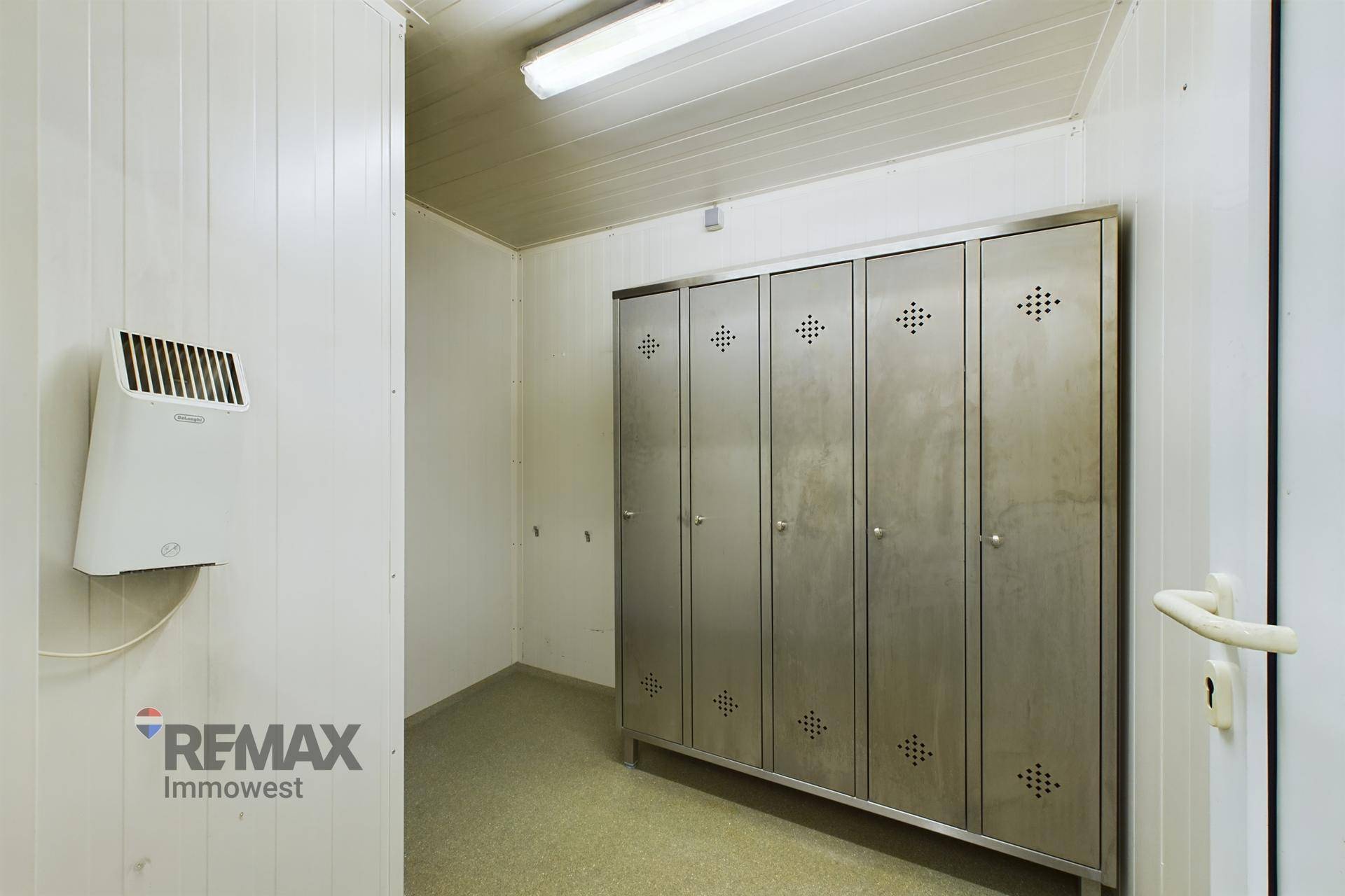 Umkleideraum mit Metallschränken und einem Händetrockner an der Wand, praktisch für Mitarbeiter.