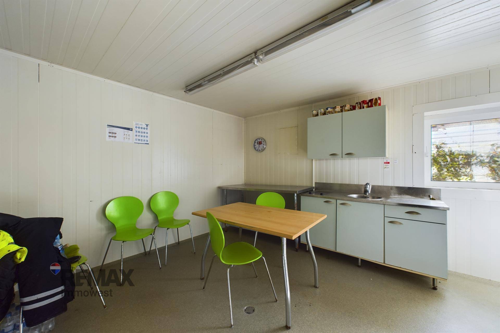 Gemütliche Teeküche mit hellgrünen Stühlen, Holztisch und blauen Schränken, ideal für Pausen.
