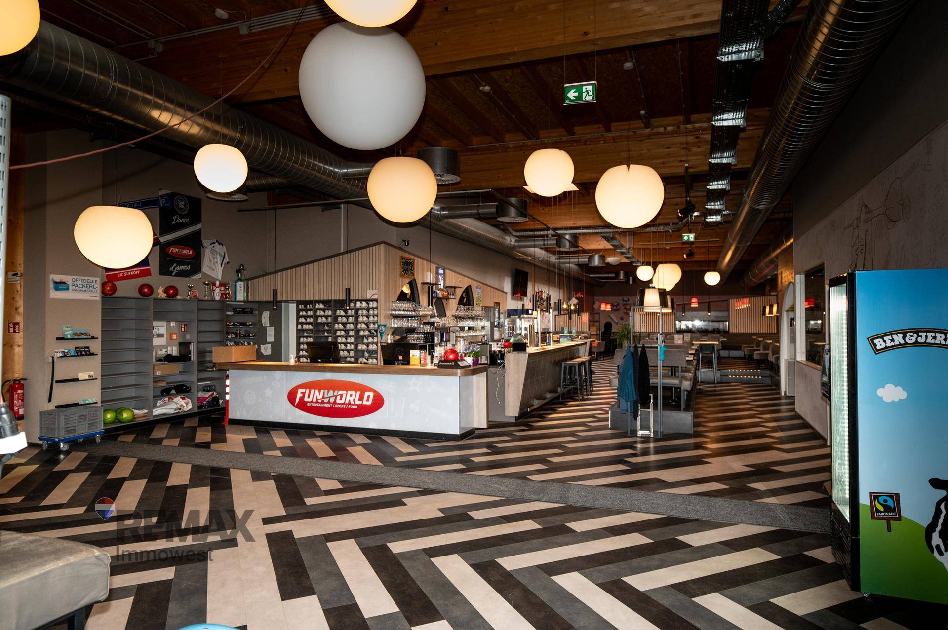 Empfangsbereich mit Bar, Sitzgelegenheiten und auffälligem Bodenmuster, ideal für Gäste.