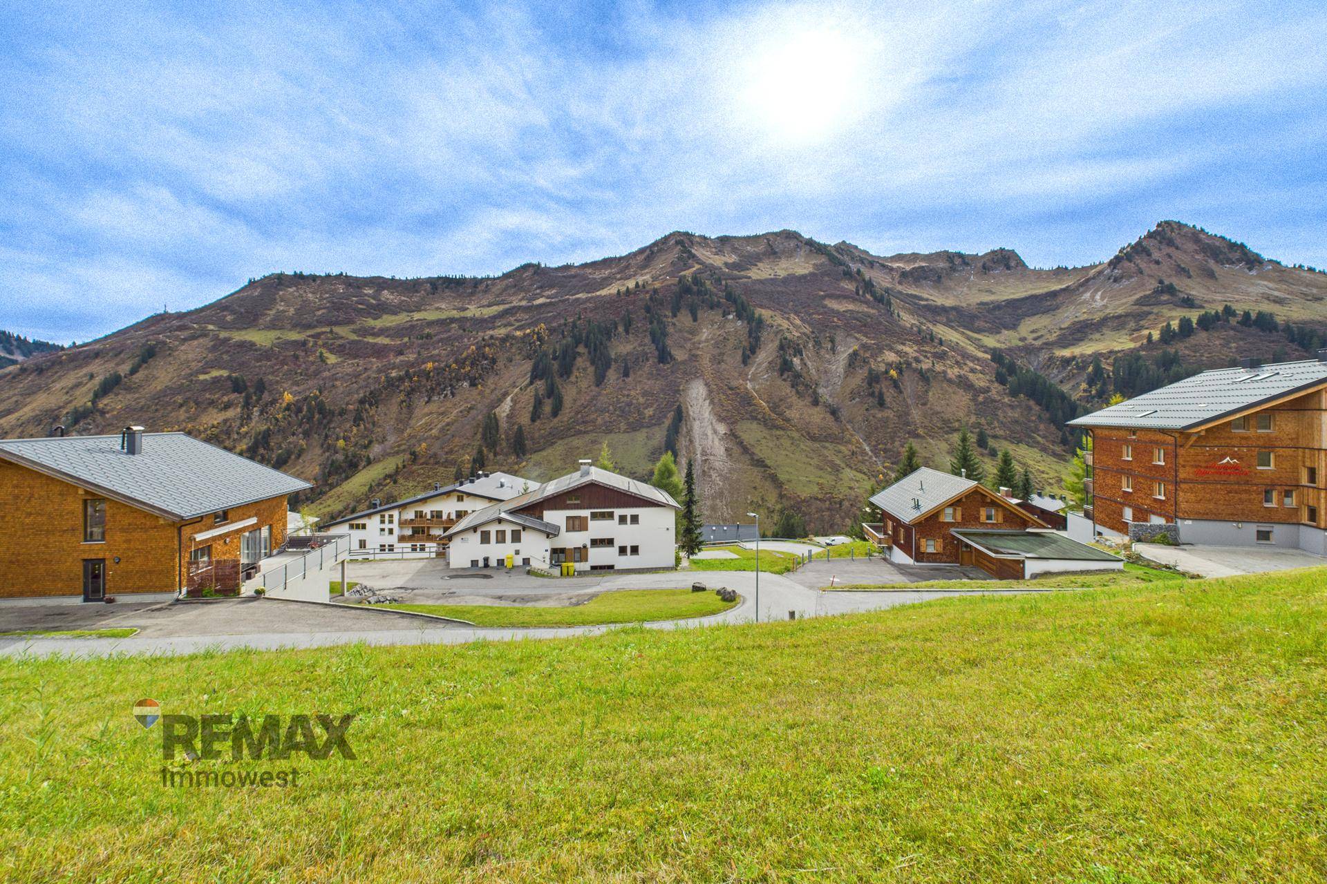 Mehrere Gebäude in einer alpinen Landschaft mit majestätischen Bergen im Hintergrund.