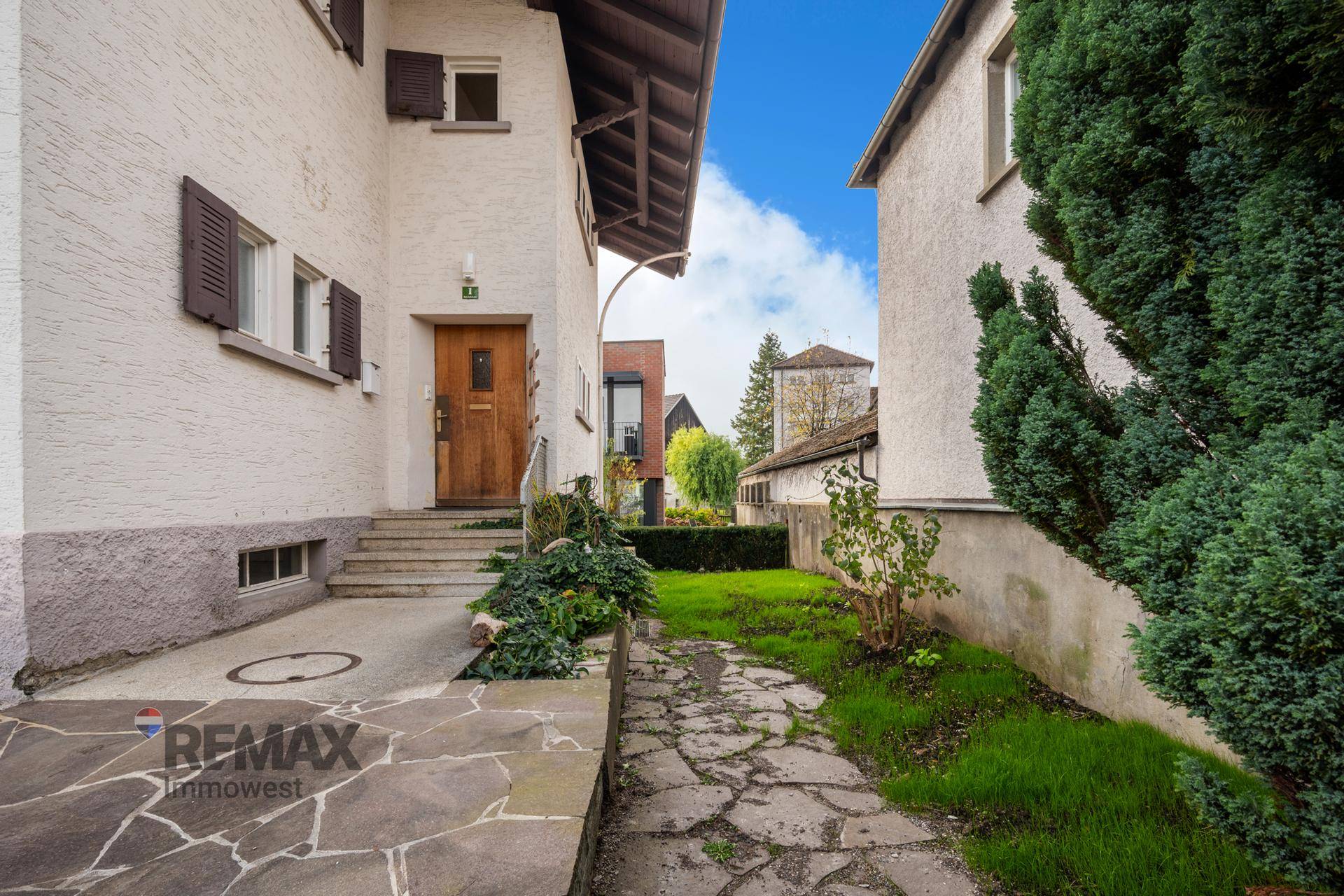 Eingangsbereich des Hauses mit Steinfliesenweg und gepflegter Bepflanzung.