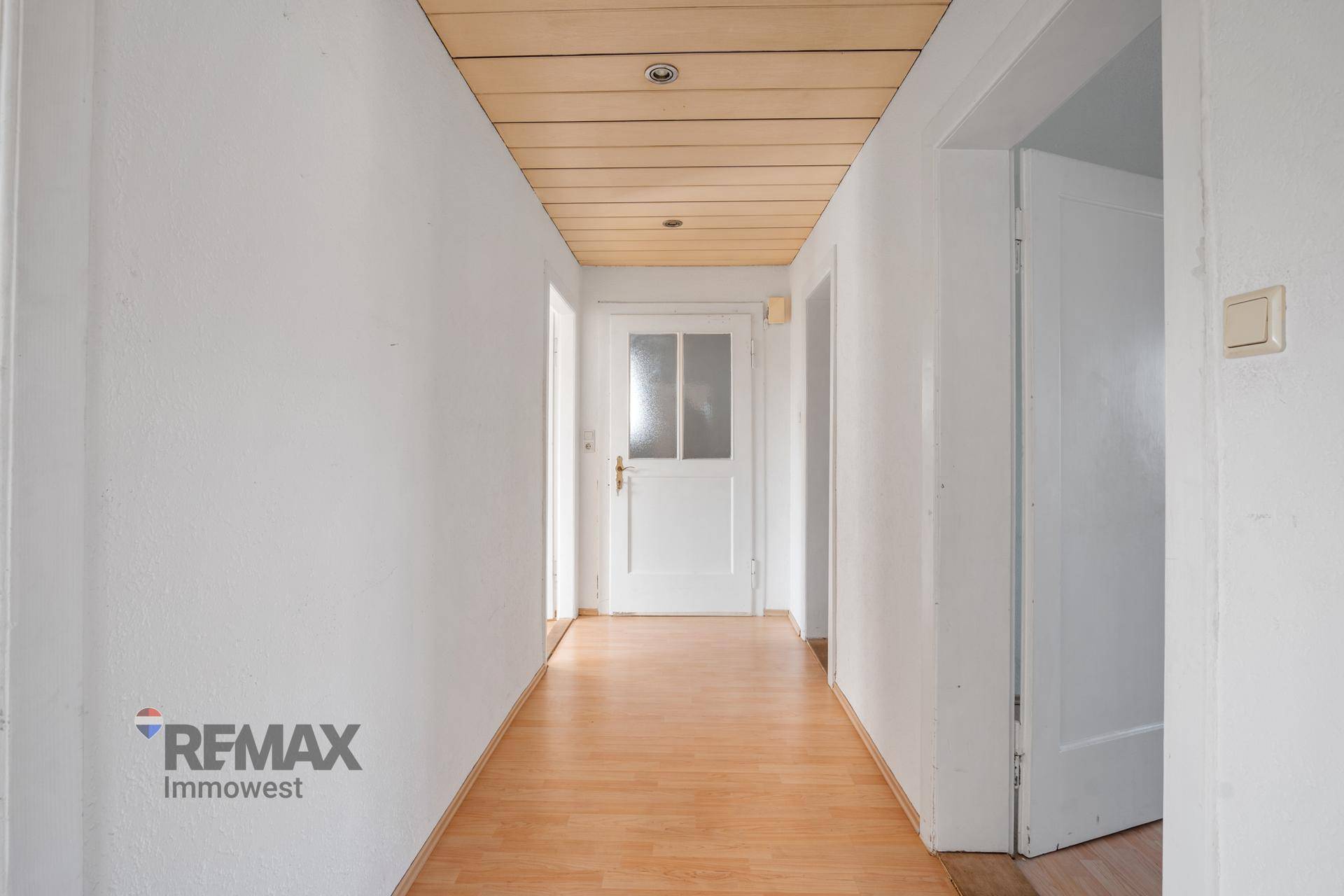 Heller Flur mit Holzdecke und Laminatboden, der zu weiteren Räumen führt.
