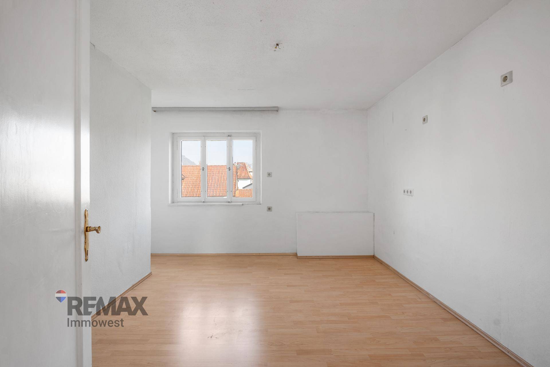 Helles Zimmer mit Laminatboden und einem Fenster, das den Raum mit Tageslicht versorgt.