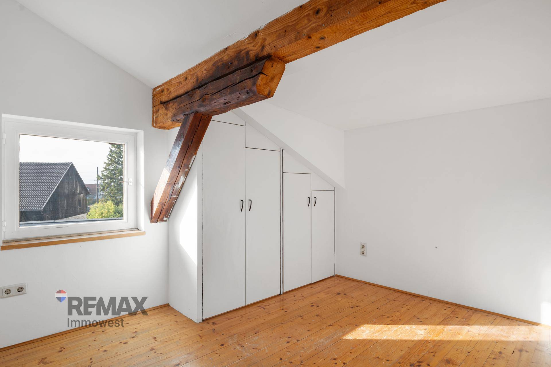 Ausgebauter Dachboden mit schrägen Wänden, Holzbalken und integrierten Schränken.