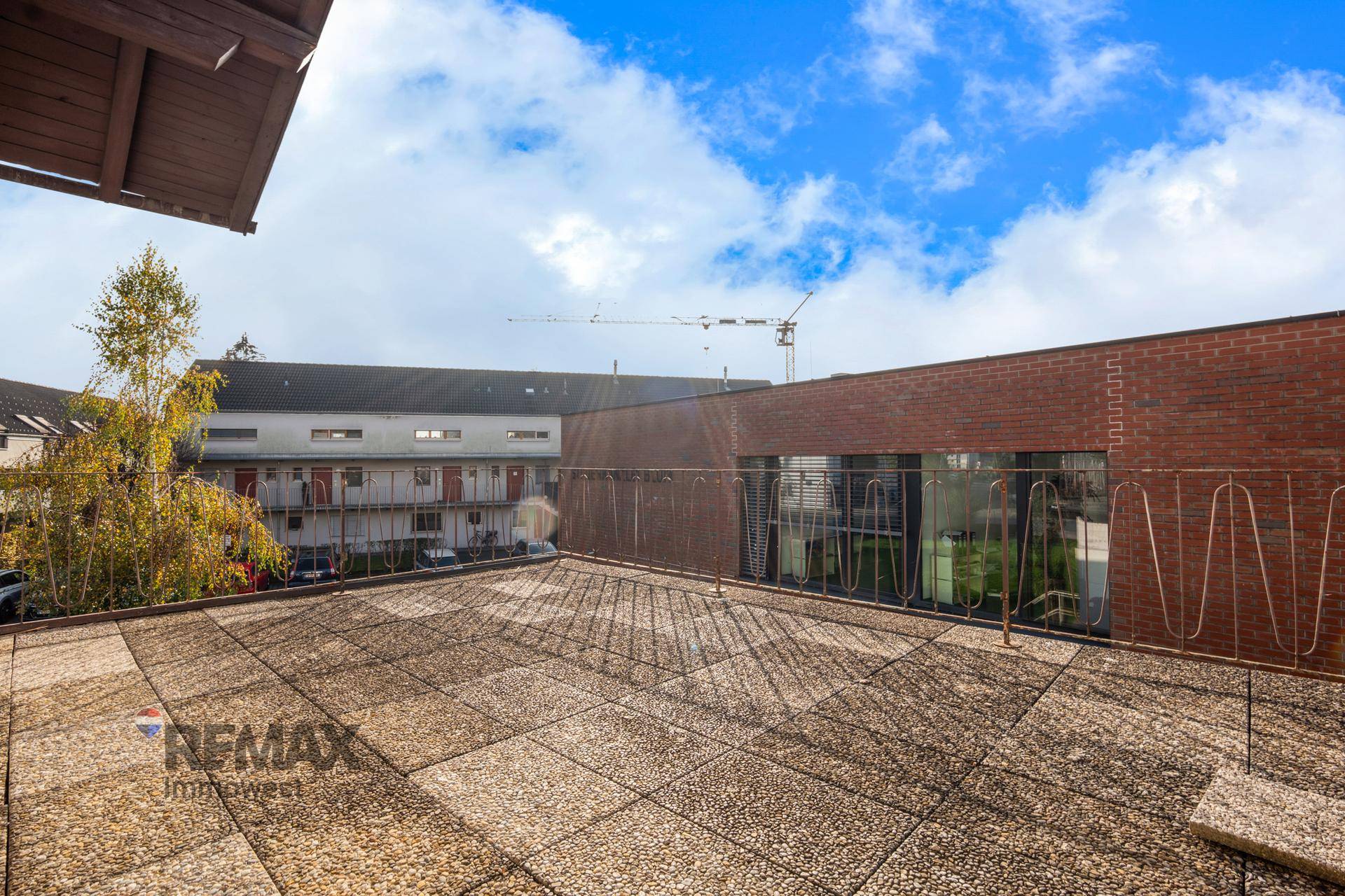 Große Dachterrasse mit Steinplatten und Blick auf die umliegenden Gebäude und den Himmel.