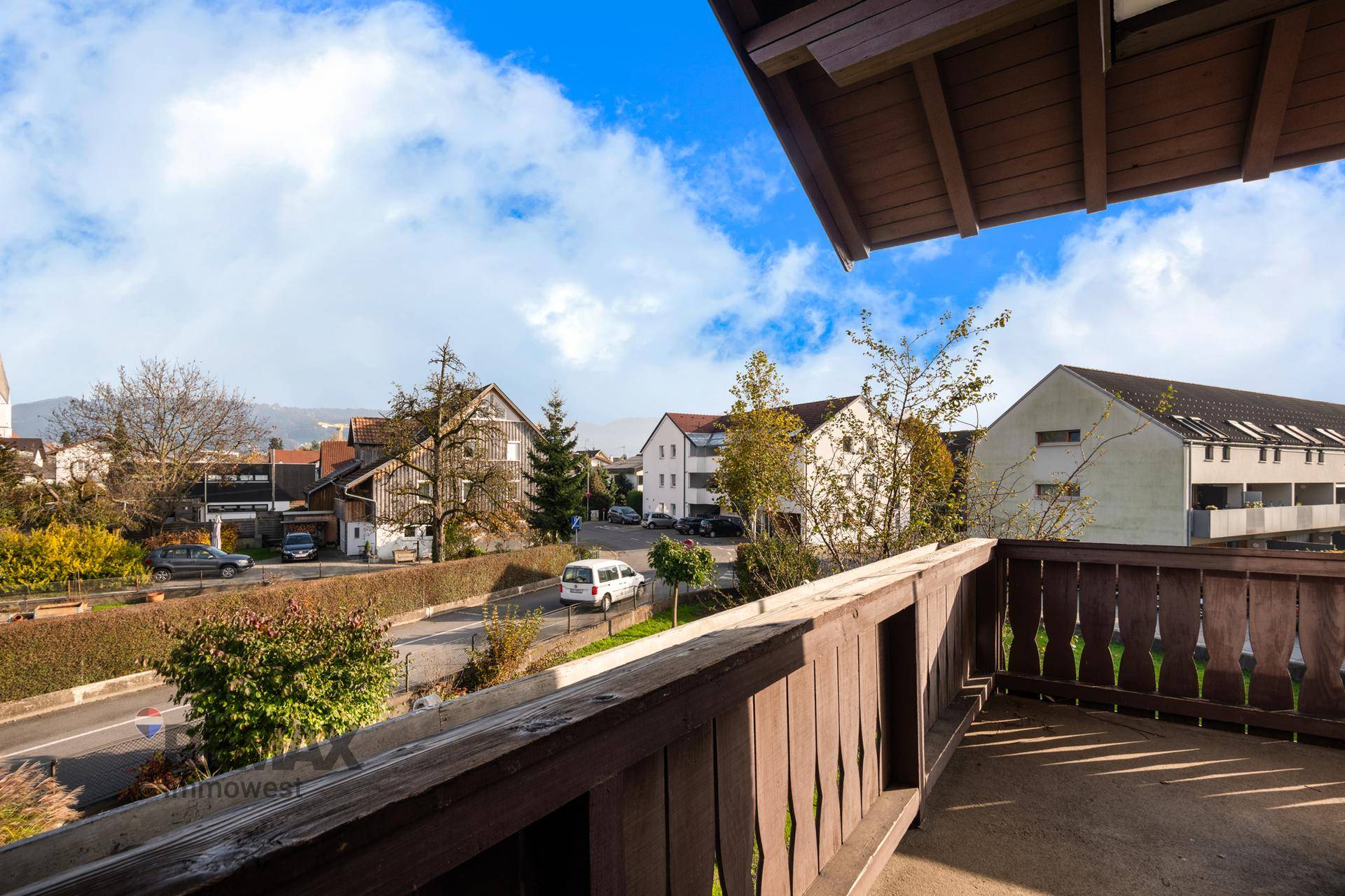 Balkon mit Holzgeländer und weitem Blick über die Dächer der umliegenden Häuser.