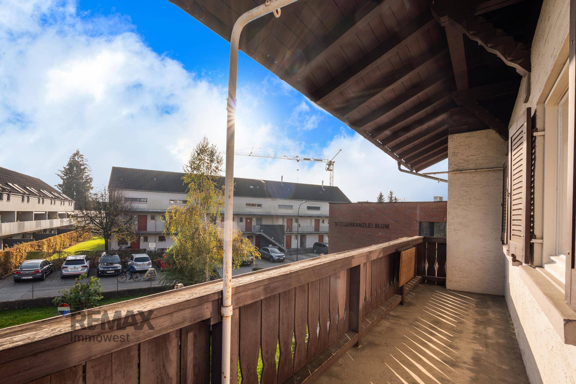 Balkon mit Holzgeländer und Blick auf die Nachbarschaft und den Parkplatz.