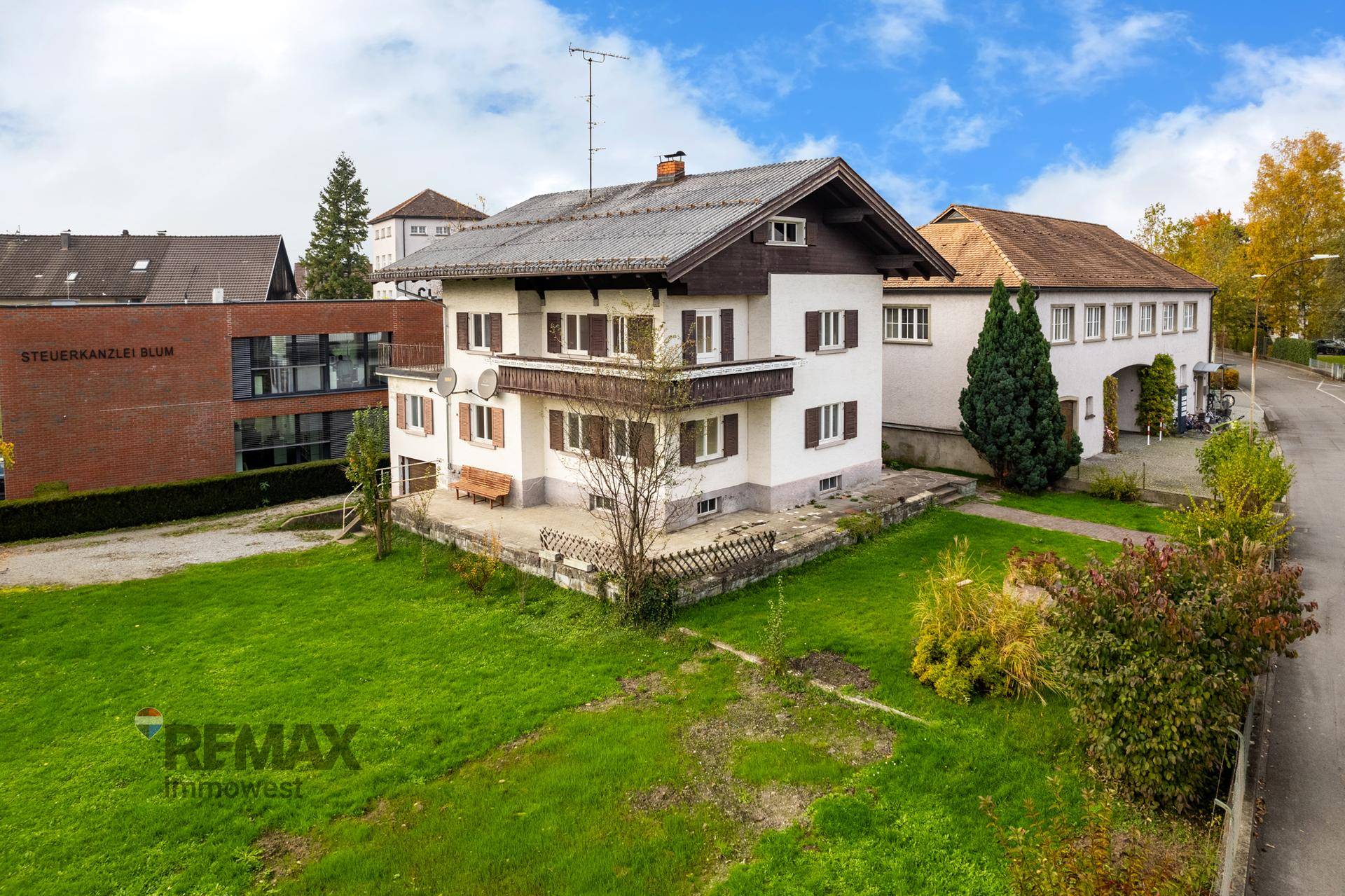 Luftaufnahme eines gepflegten Einfamilienhauses mit Satteldach, Balkon, Terrasse und Gartenfläche.