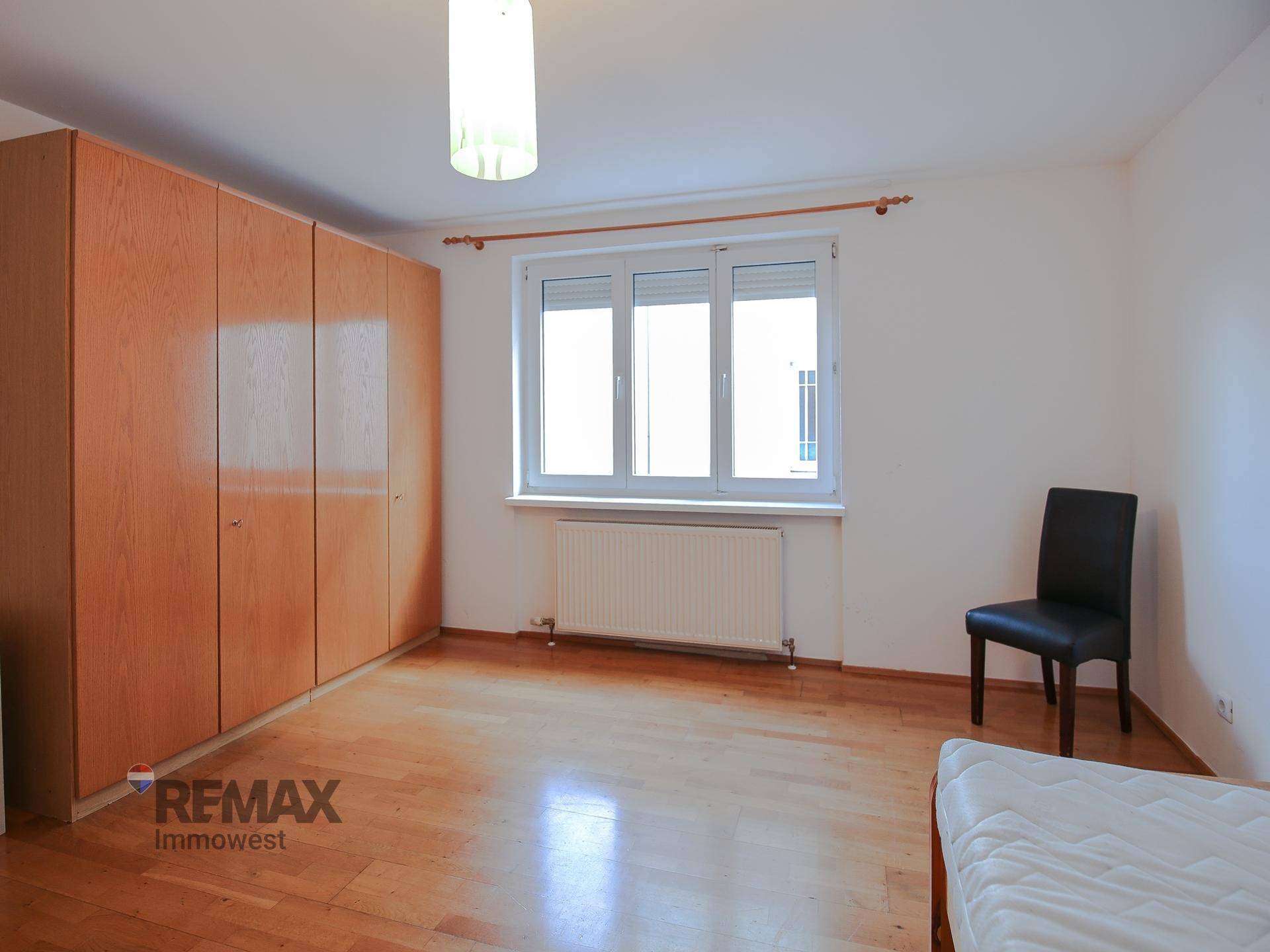 Geräumiges Schlafzimmer mit Holzboden, großem Kleiderschrank und einem Fenster.