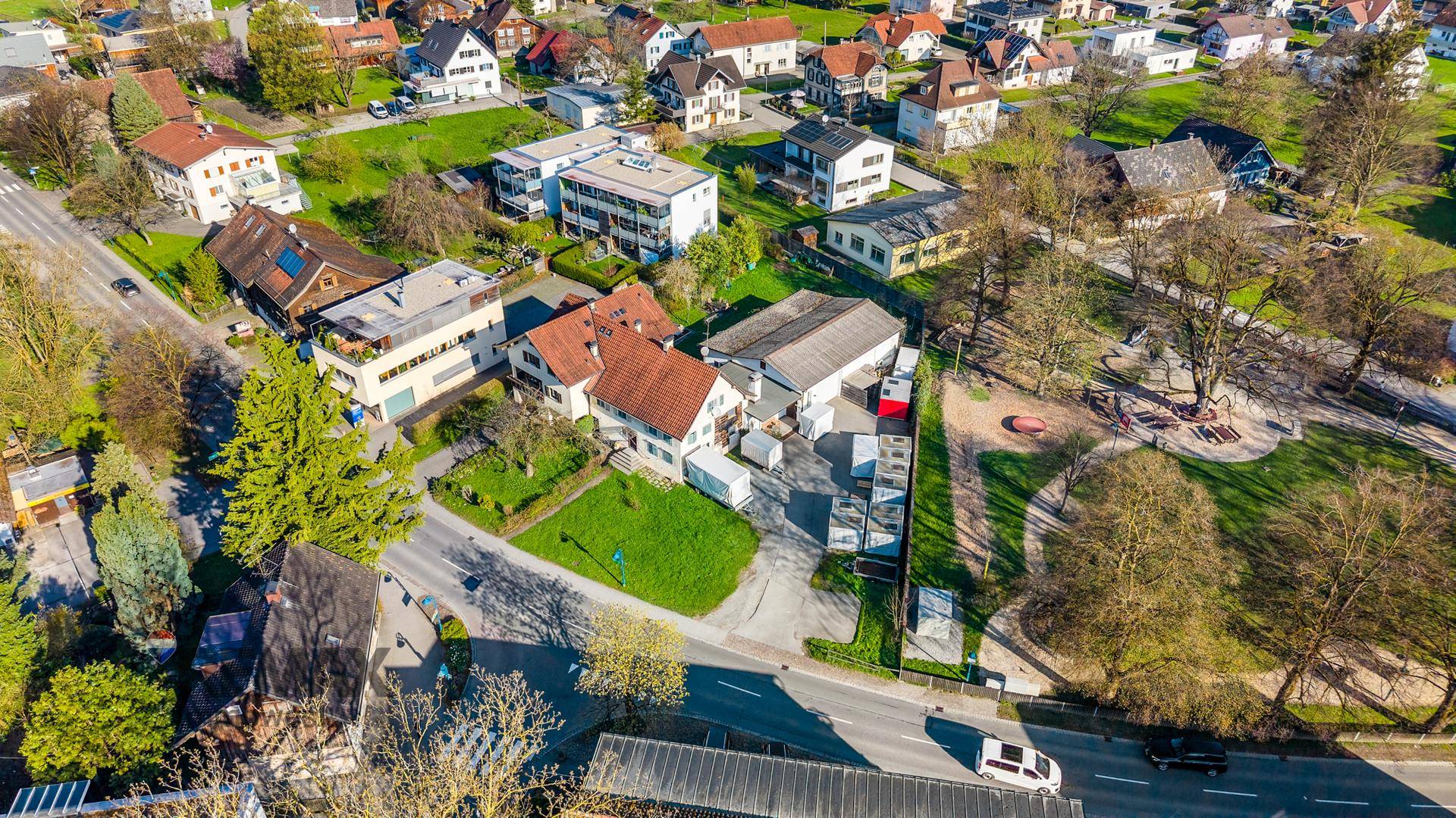 Luftaufnahme eines Wohngebiets mit Häusern, Gärten und Straßen in sonniger Umgebung.