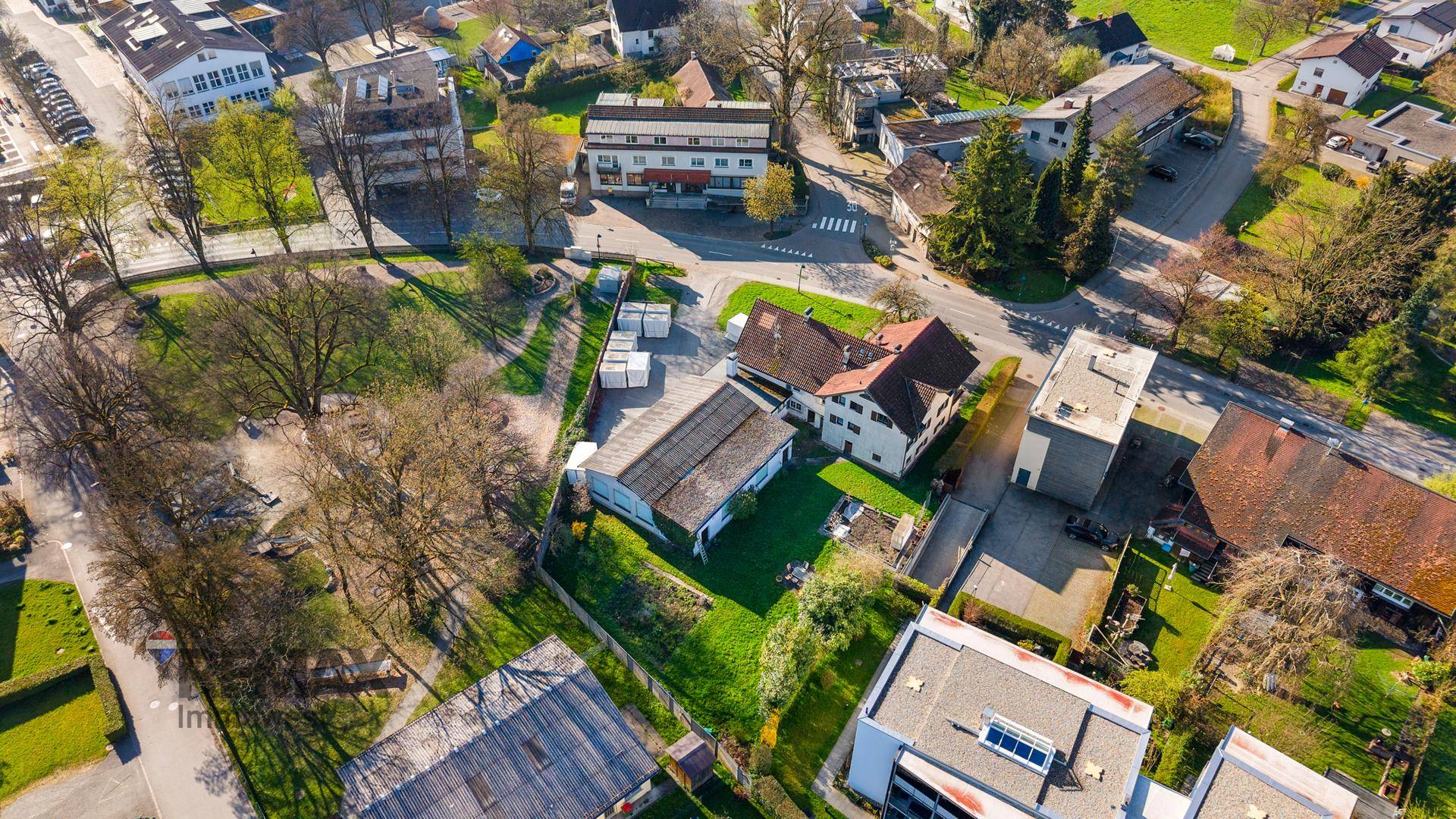Luftaufnahme eines Wohngebiets mit Häusern, Gärten und Straßen in sonniger Umgebung.
