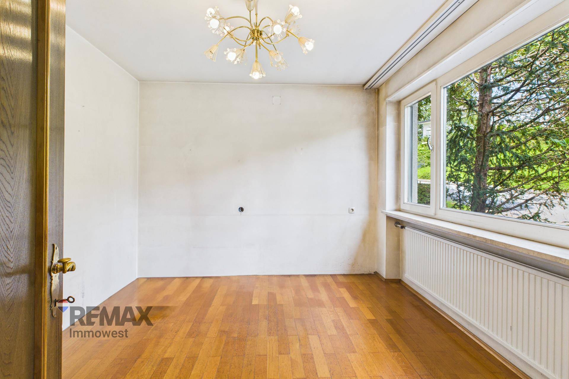 Helles Zimmer mit Parkettboden, großem Fenster und Heizkörper, bereit zur individuellen Gestaltung.