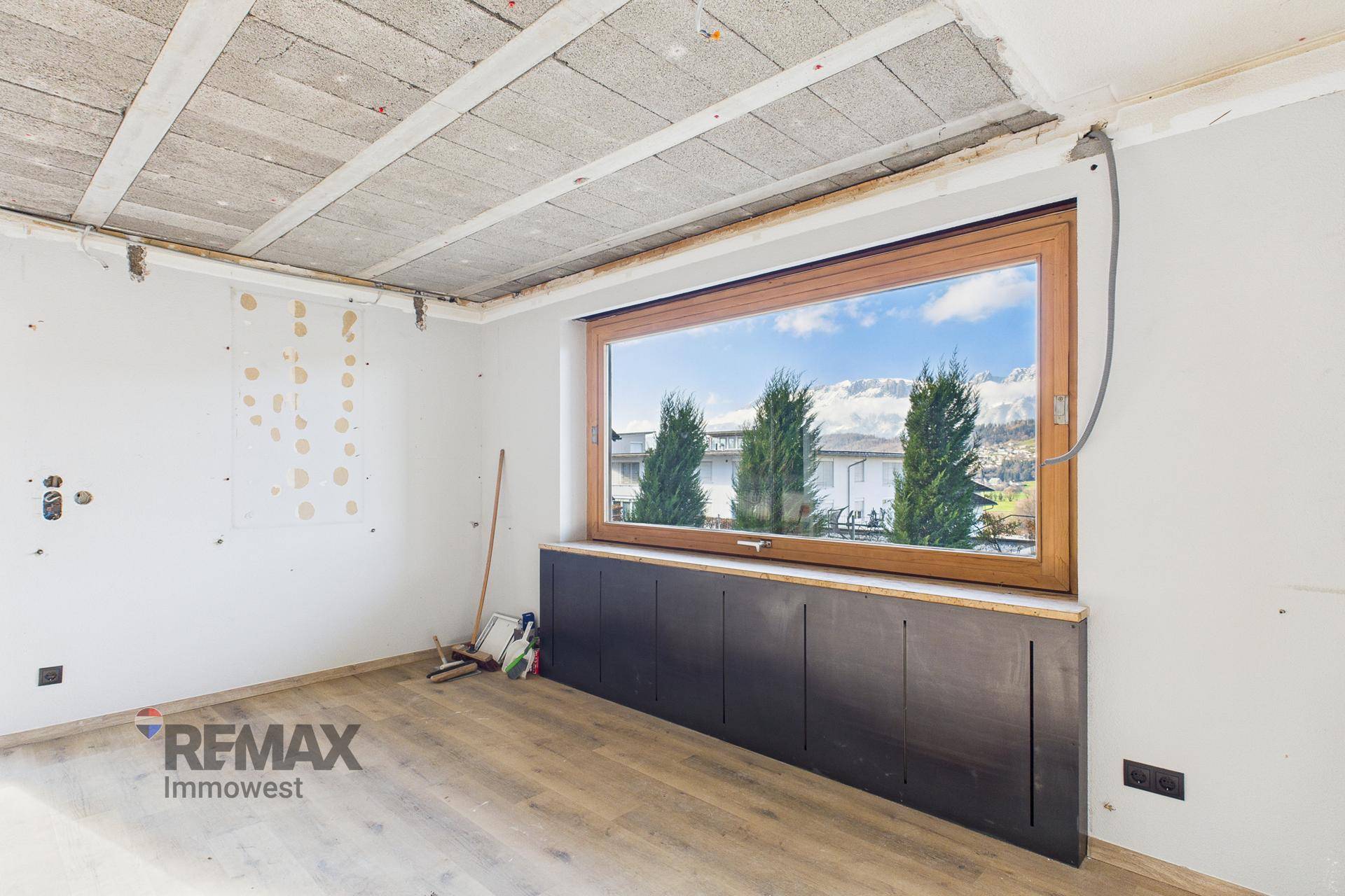 Heller Raum im Rohbau mit großem Fenster und Blick ins Grüne, ideal für individuelle Gestaltung.