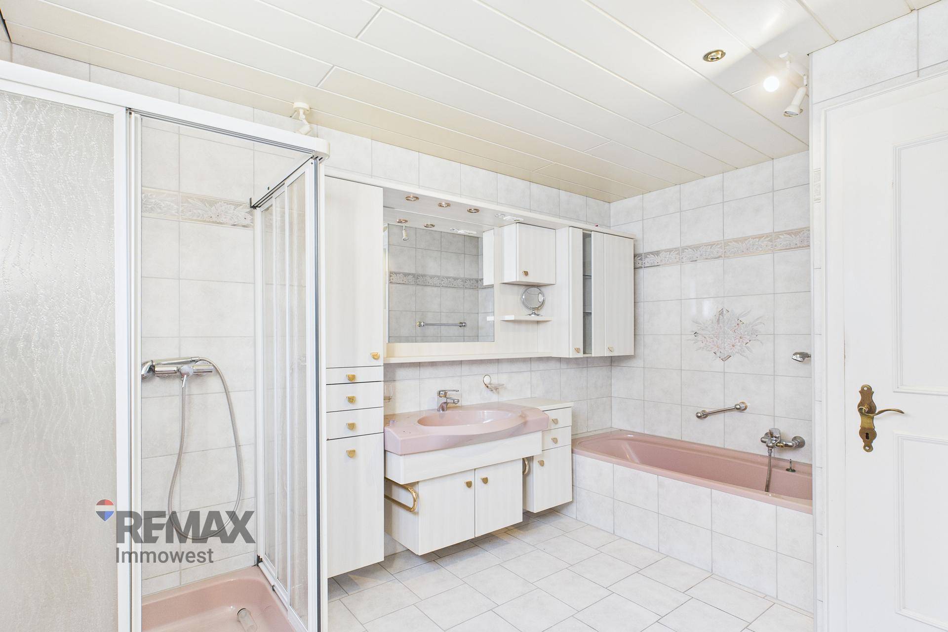 Badezimmer im Retro-Stil mit Badewanne, Duschkabine und rosa Sanitärobjekten.