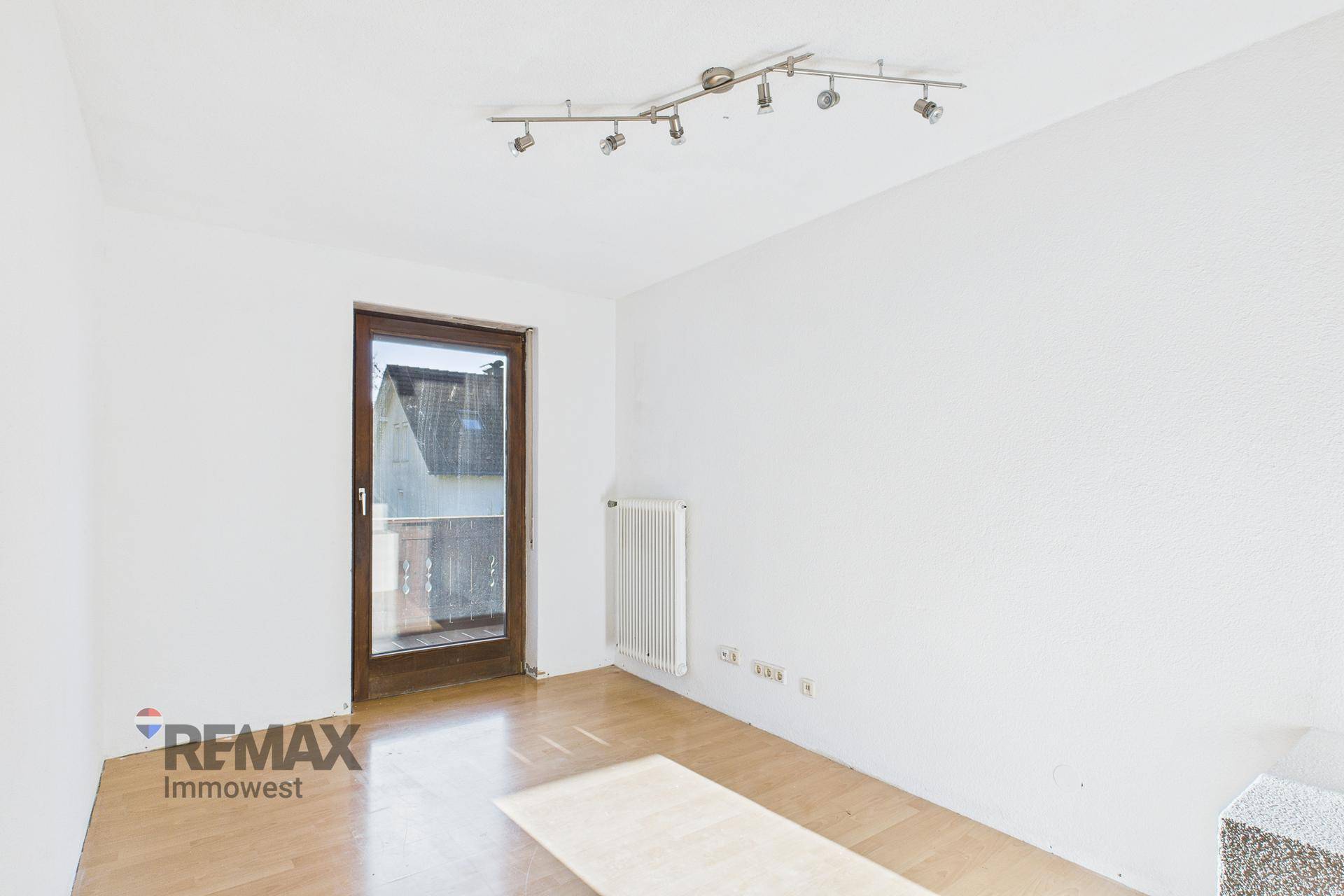 Heller Raum mit Holzboden und Balkontür, ideal für ein Kinderzimmer oder Büro.