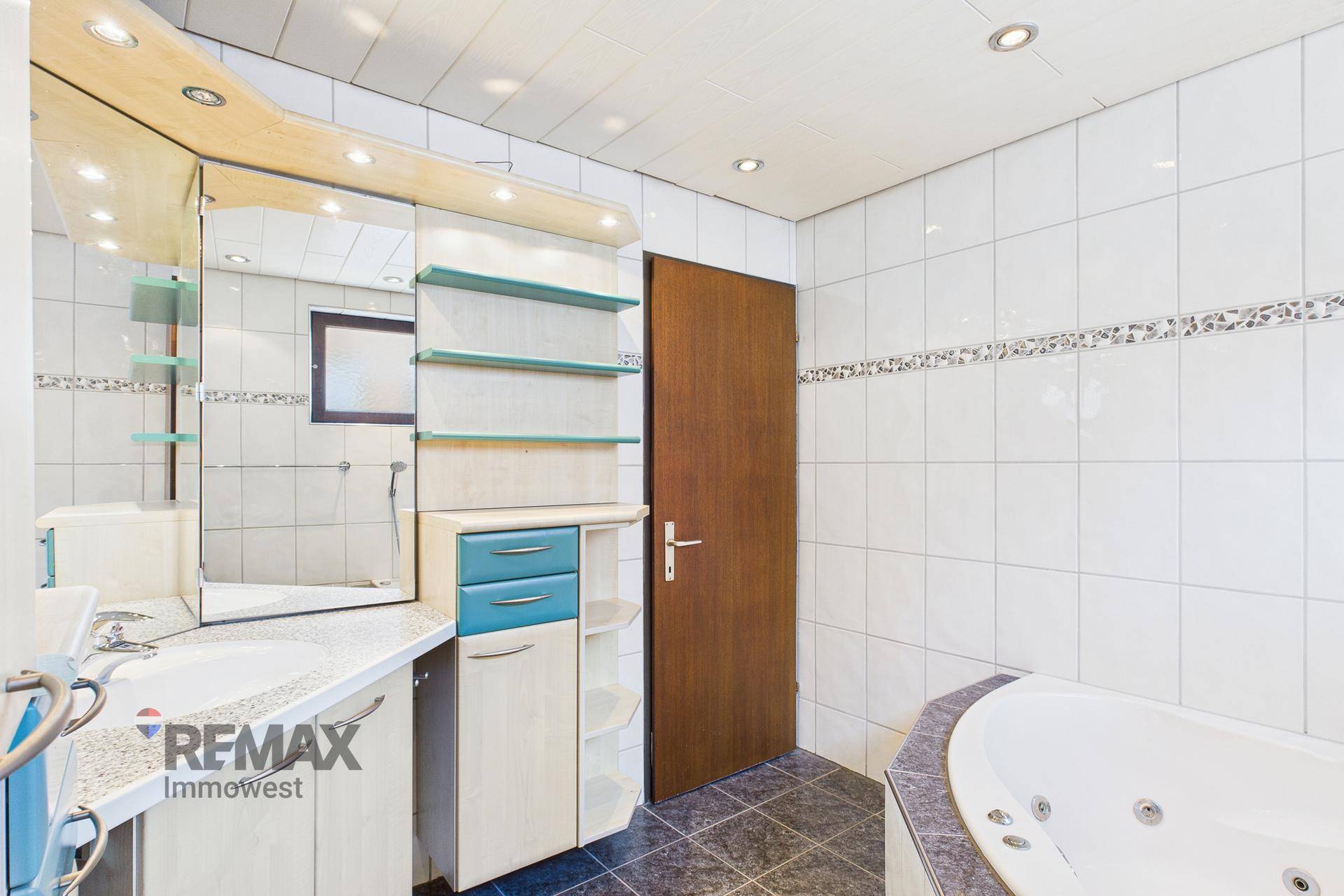 Geräumiges Badezimmer mit Eckbadewanne, Doppelwaschbecken und modernen Einbaumöbeln.