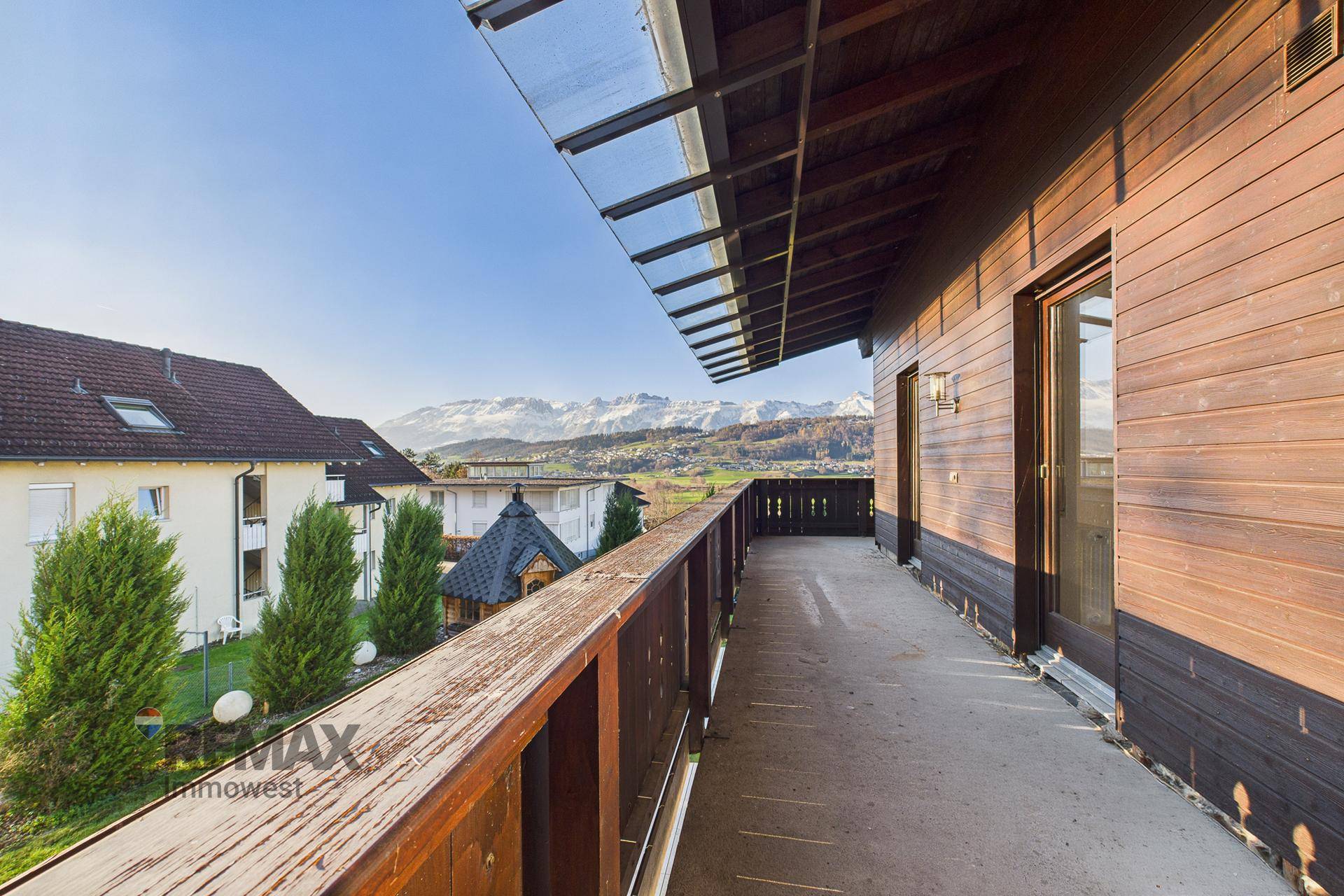 Langer Holzbalkon mit Panoramablick auf die schneebedeckten Berge und die umliegende Landschaft.