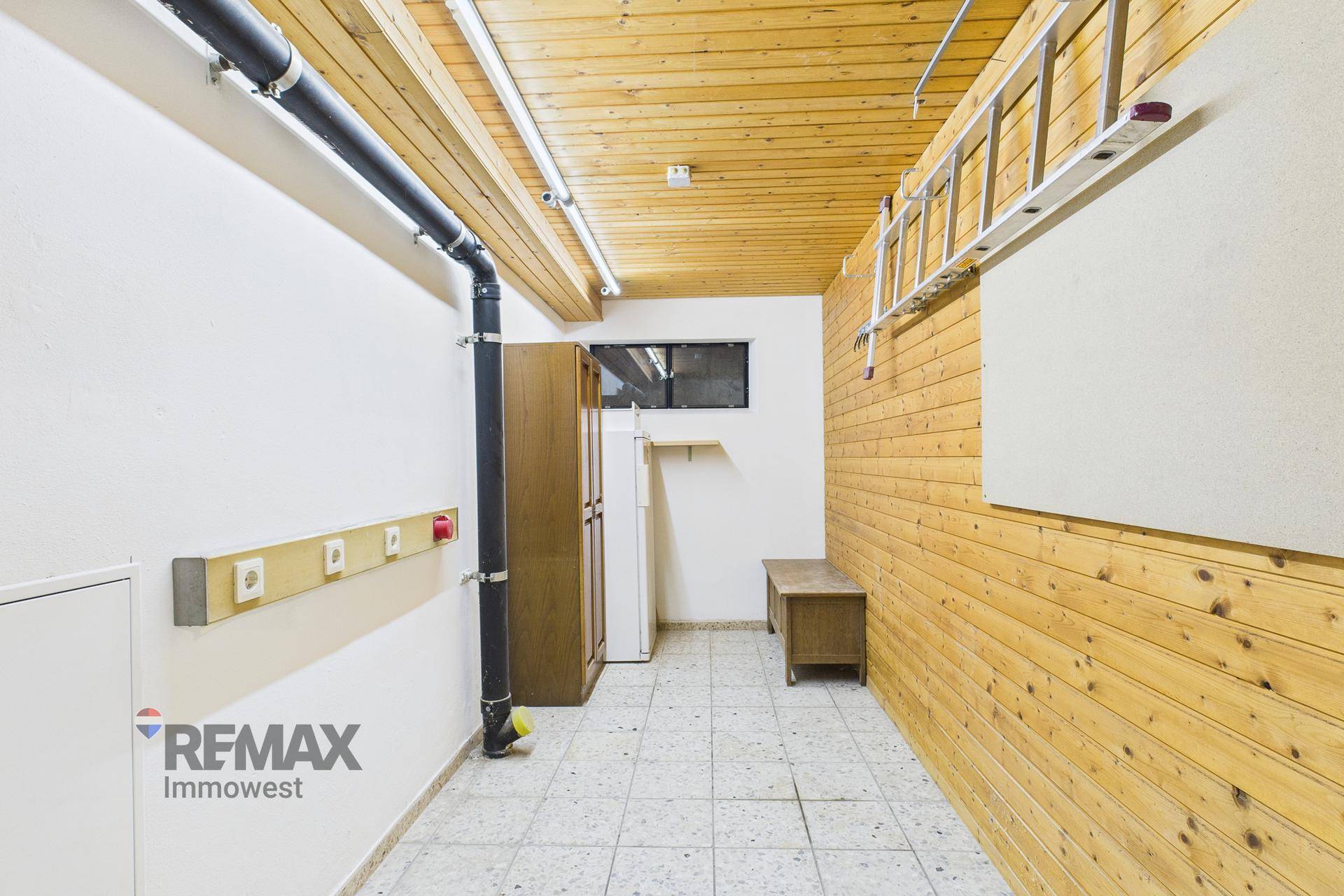 Praktischer Abstellraum mit Holzverkleidung an Decke und Wand sowie funktionalem Fliesenboden.