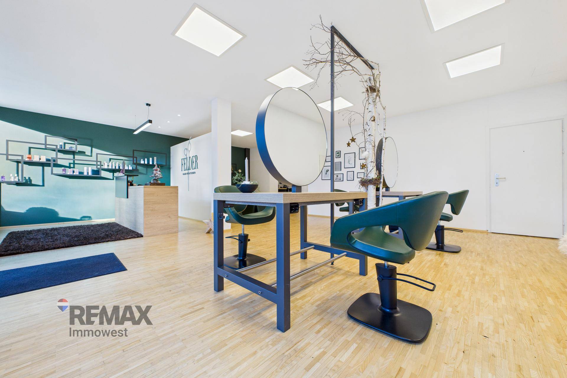 Stylingbereich mit modernen Friseurstühlen, runden Spiegeln und Blick zum Empfang.