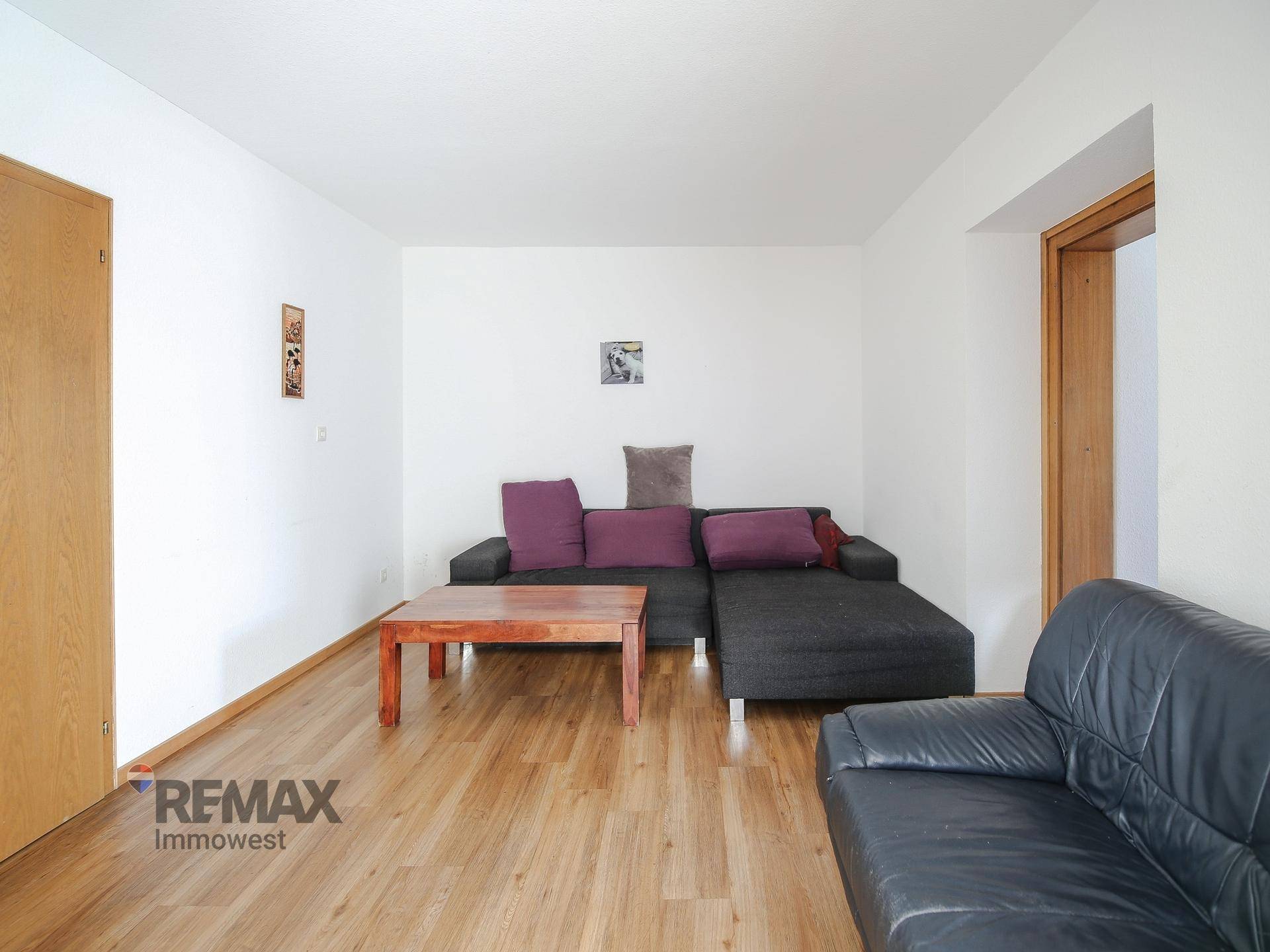 Gemütliches Wohnzimmer mit Holzboden, dunklem Sofa und Holztisch.