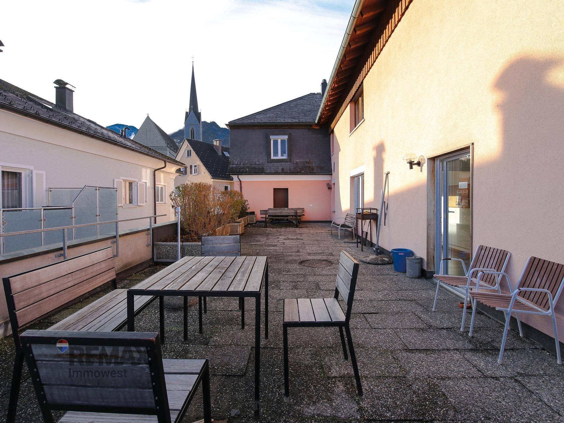 Große gepflasterte Terrasse mit Gartenmöbeln und Blick auf die Umgebung.