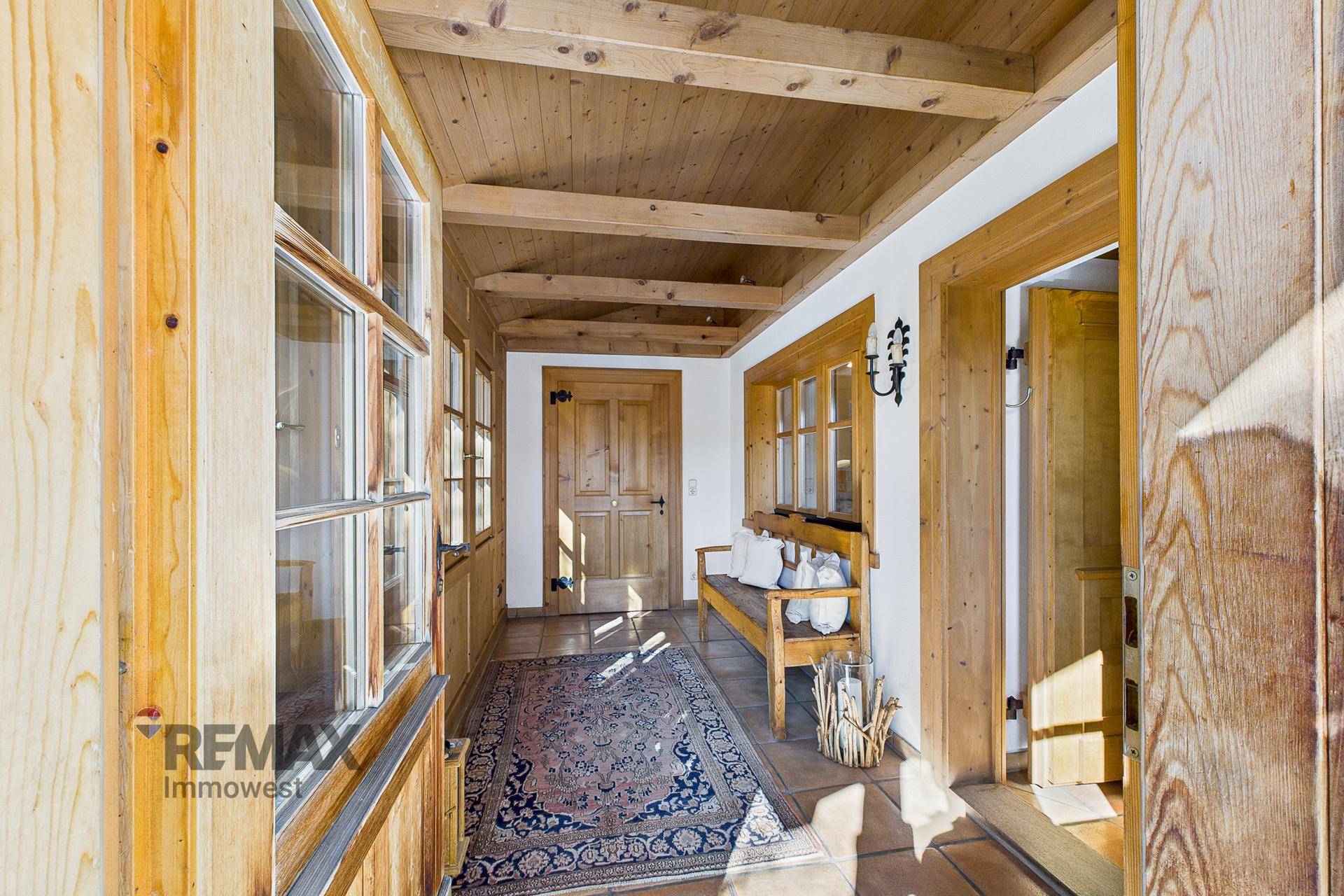 Gemütlicher Flur mit Holzbalkendecke, rustikalen Holzmöbeln und traditionellem Teppich.