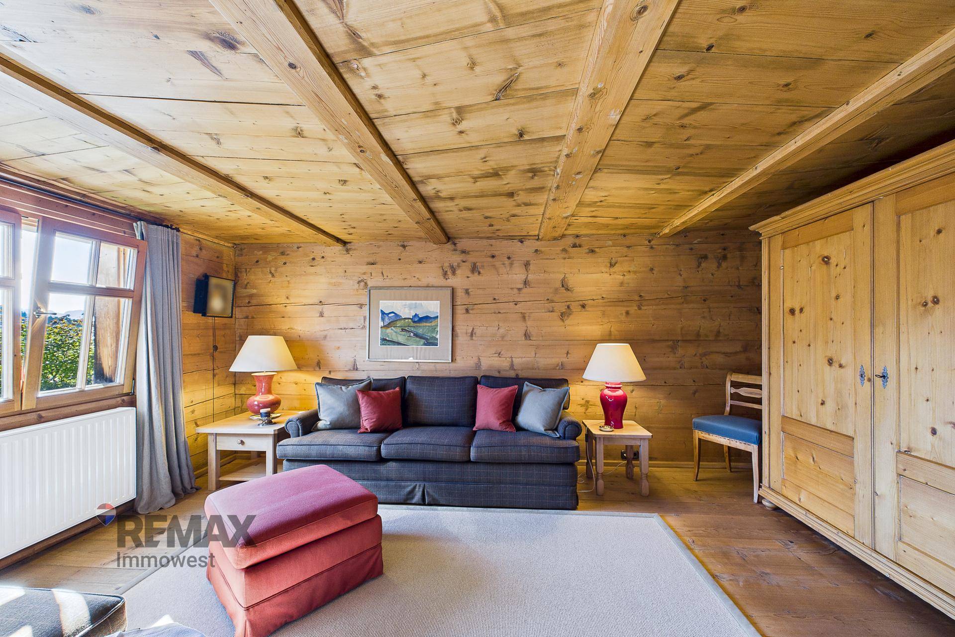 Wohnzimmer im alpinen Stil mit Holzwänden, bequemen Sitzgelegenheiten und traditionellem Kleiderschrank.