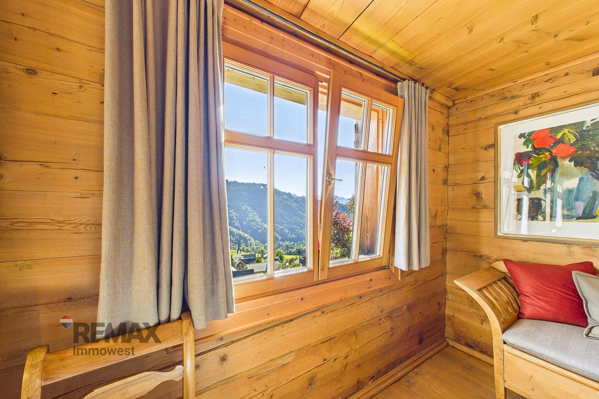 Fenster mit Holzrahmen bietet einen malerischen Blick auf die grünen Berge und das Tal.