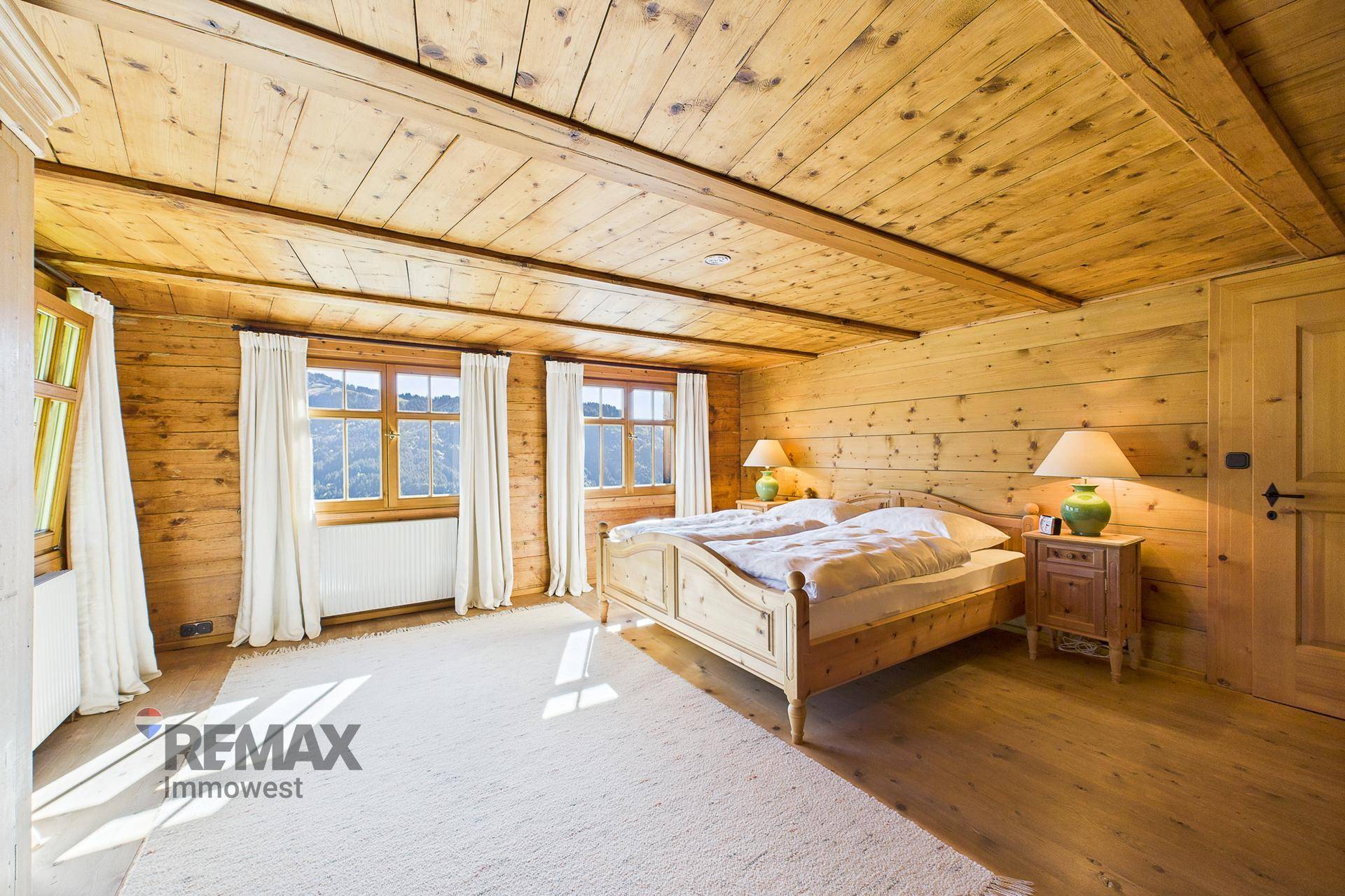 Gemütliches Schlafzimmer mit Holzwänden und -decke, Doppelbett und Blick auf die Landschaft.