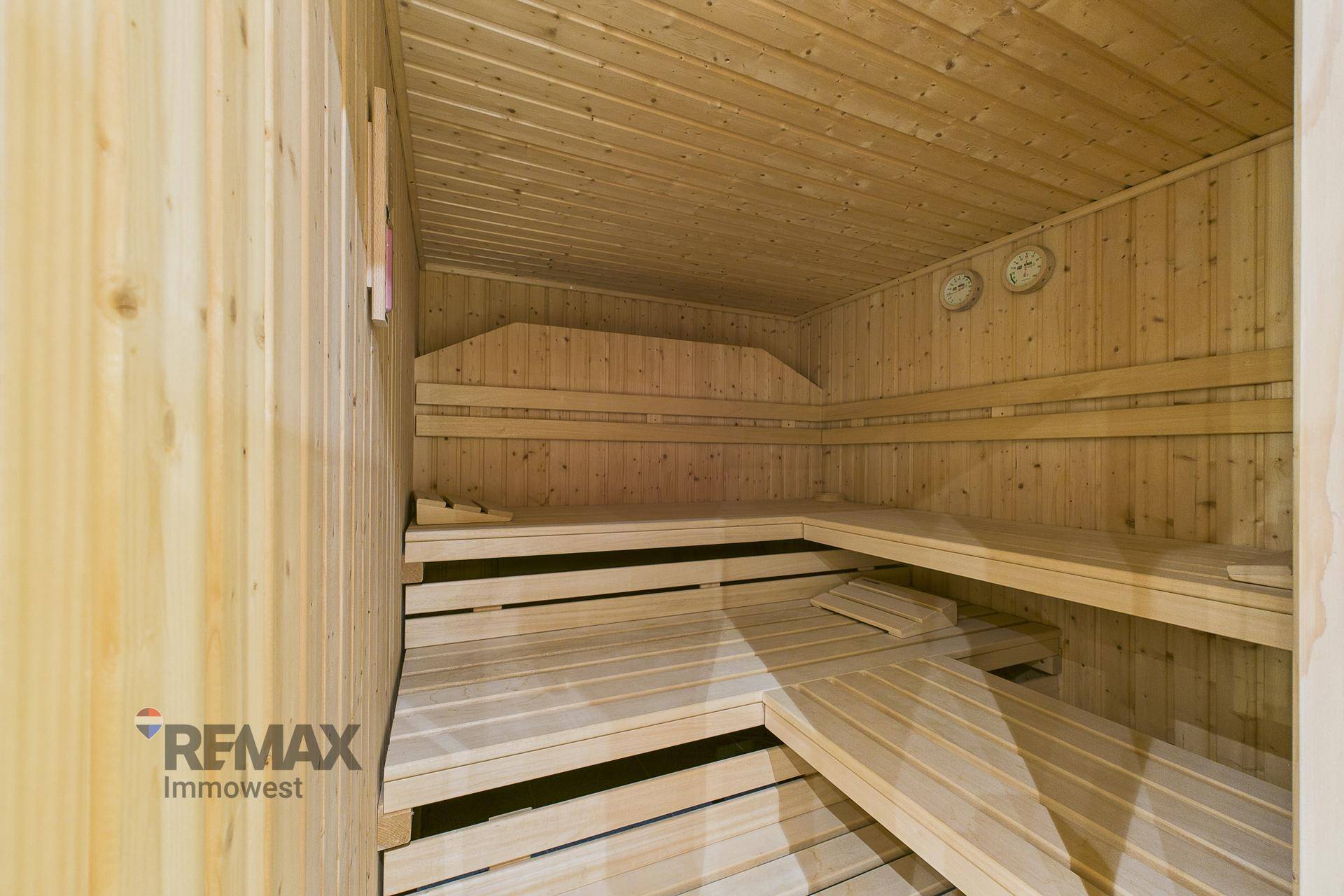 Traditionelle Holzsauna mit mehrstufigen Bänken und Temperaturanzeigen für entspannende Momente.