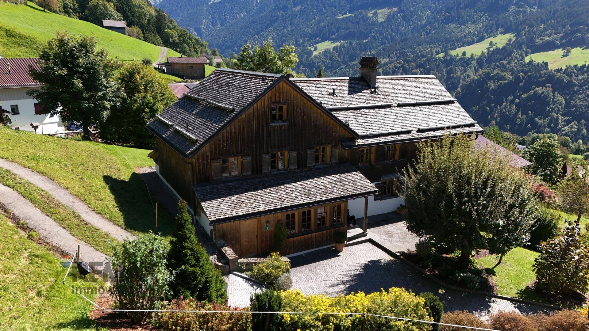 Charmantes Holzhaus mit traditionellem Satteldach und gepflegtem Vorgarten in sonniger Berglage.