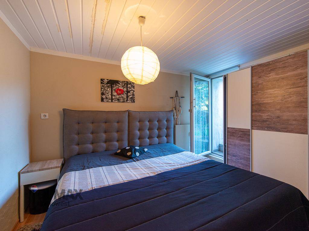 Schlafzimmer mit Doppelbett, Holzdecken und Zugang zu einem französischen Balkon.