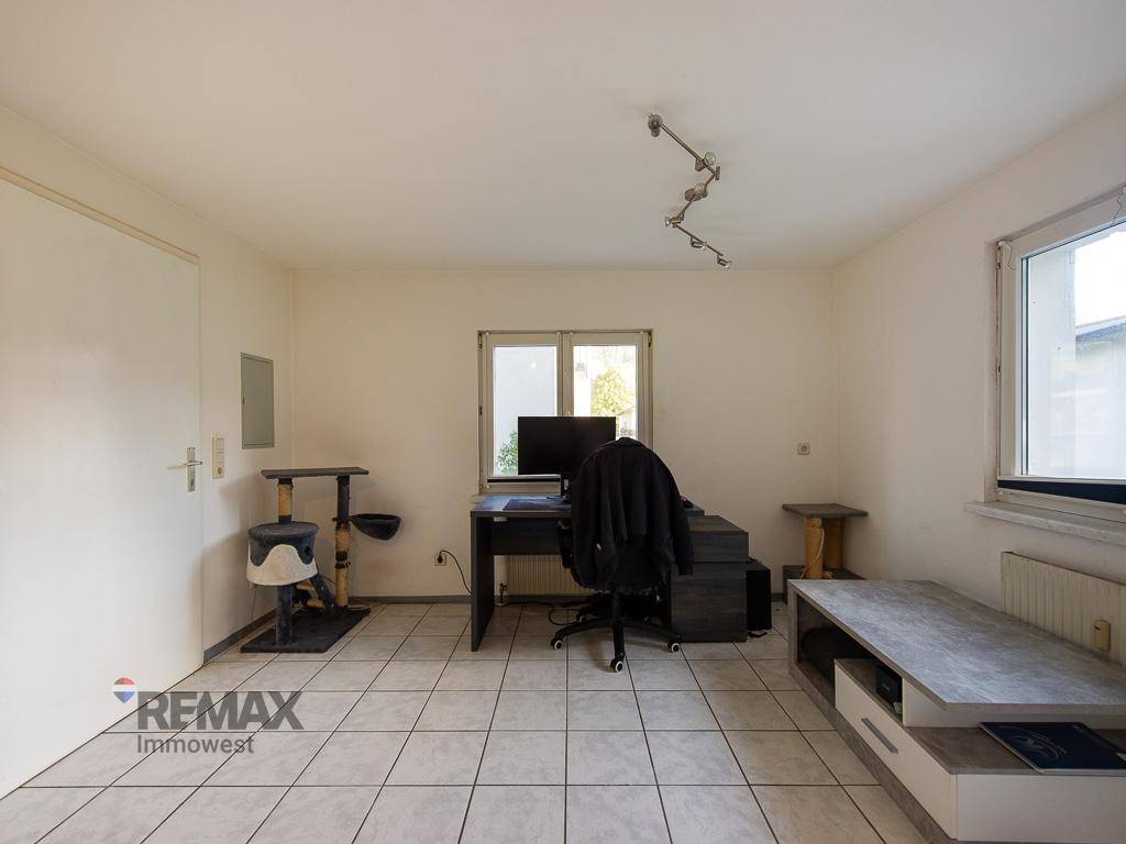 Arbeitszimmer mit Fliesenboden, Schreibtisch und Fenster.