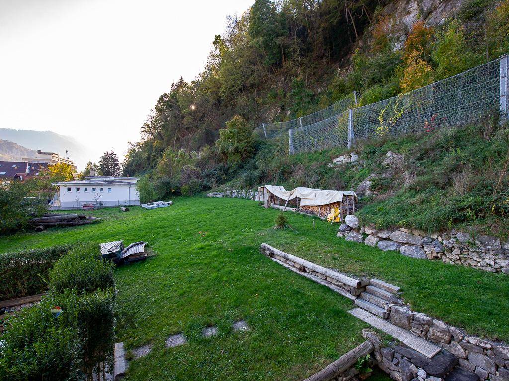 Großer Gartenbereich mit Rasenfläche und Blick auf die bewaldeten Hänge.