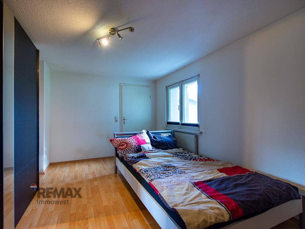 Helles Schlafzimmer mit Holzboden, Einzelbett und Fenster.